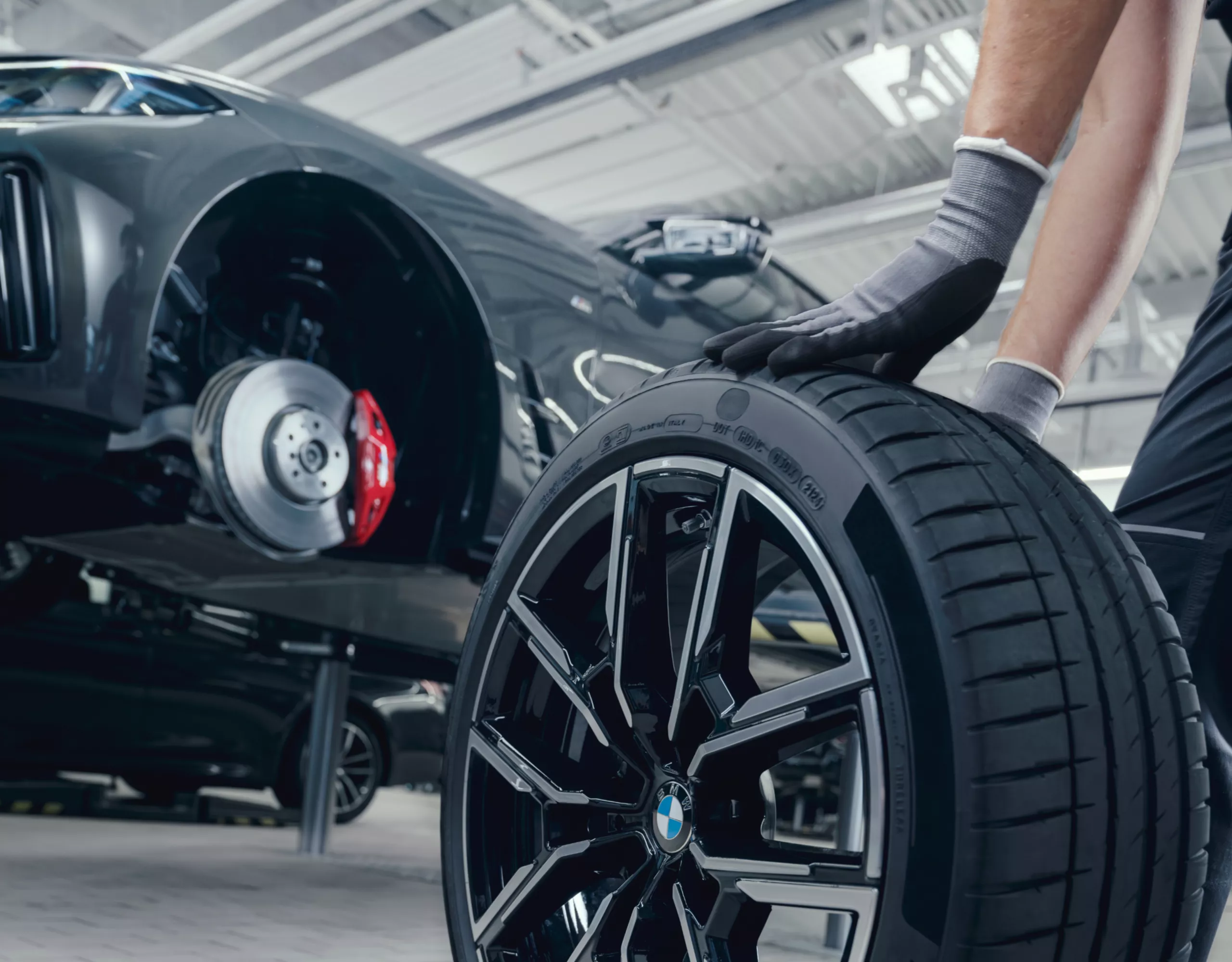 Person rollt ein Komplettrad zur Montage zum BMW