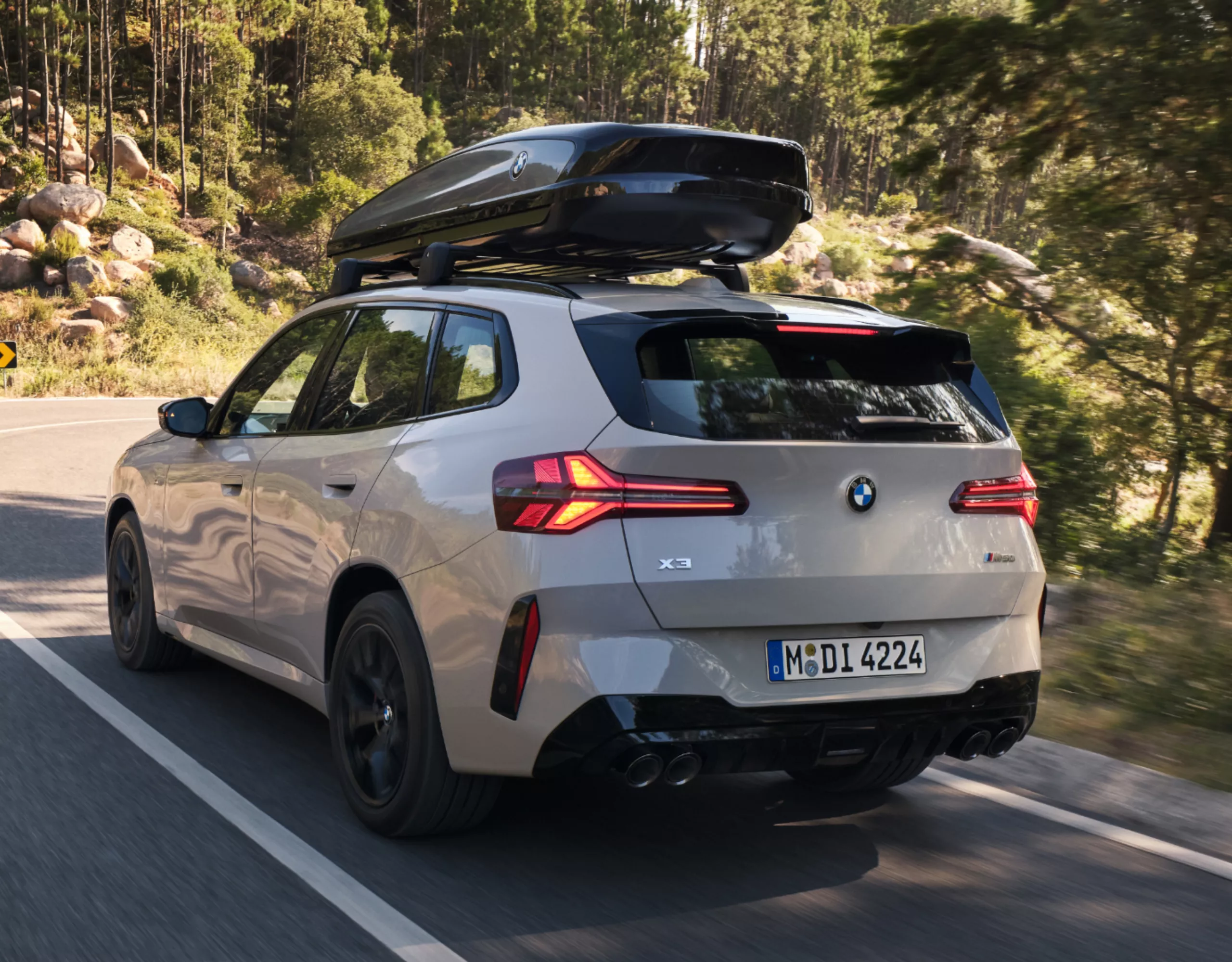 Two people standing in front of a BMW iX3 with rooftop box gazing into the distance