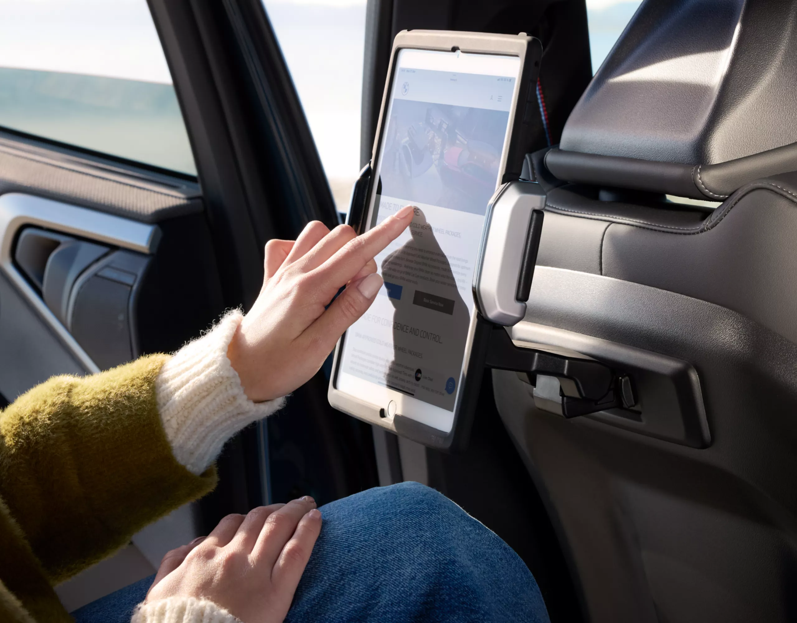 Une personne est assise dans une BMW et utilise une tablette dans un support