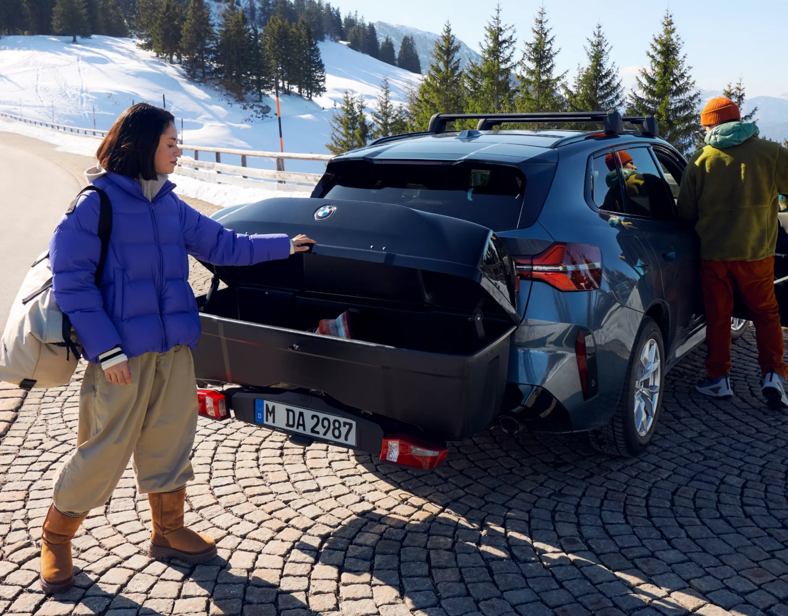 Une personne ouvre le coffre arrière sur un parking