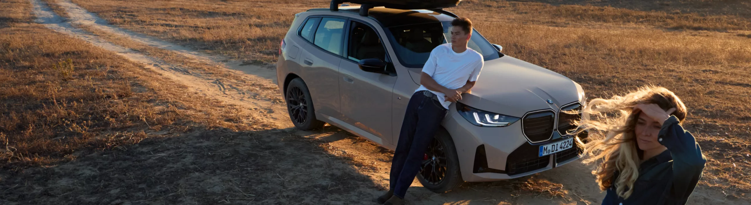 Two people drive their BMW to the beach to go jogging with their dog