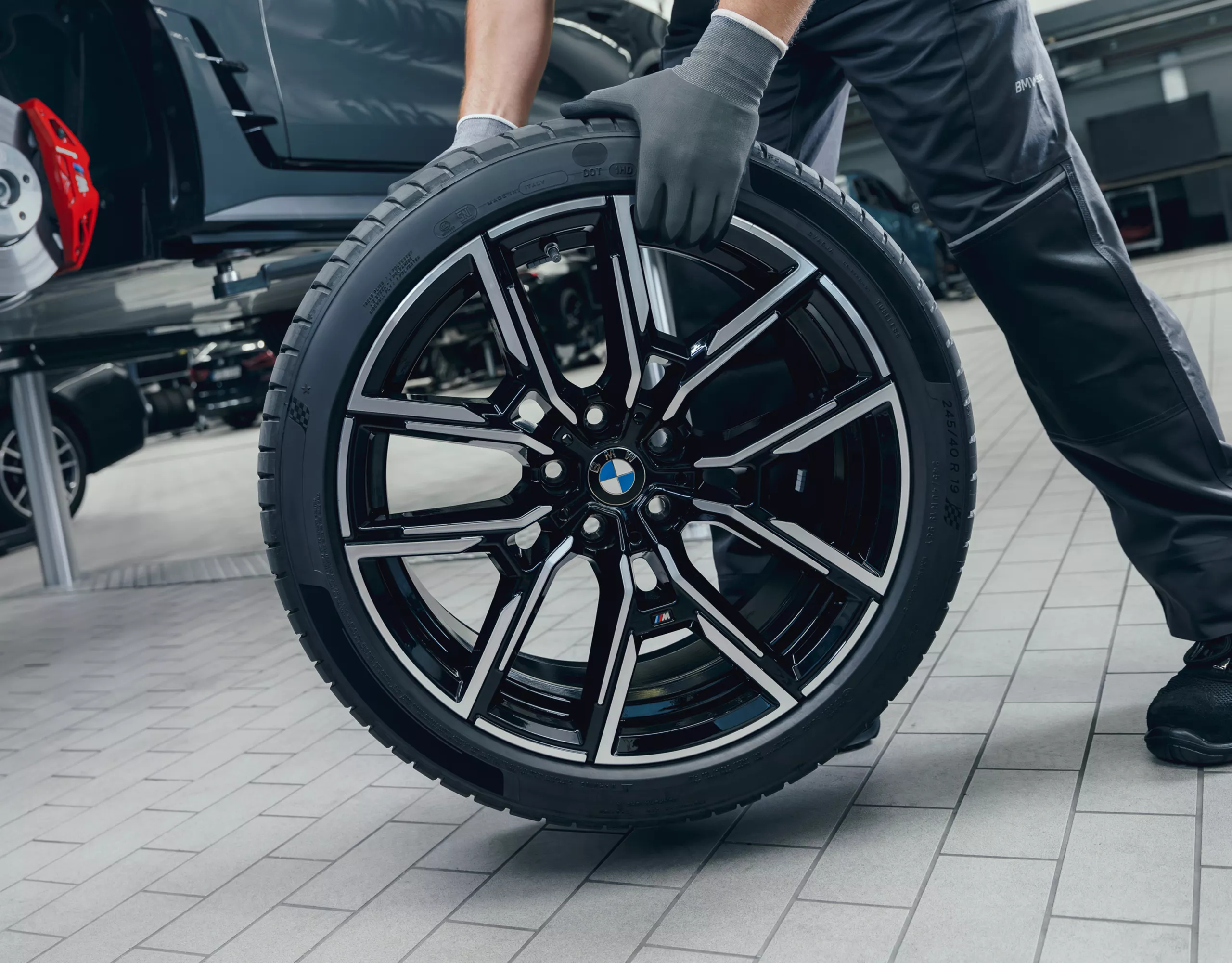 Person rollt ein Komplettrad zur Montage zum BMW