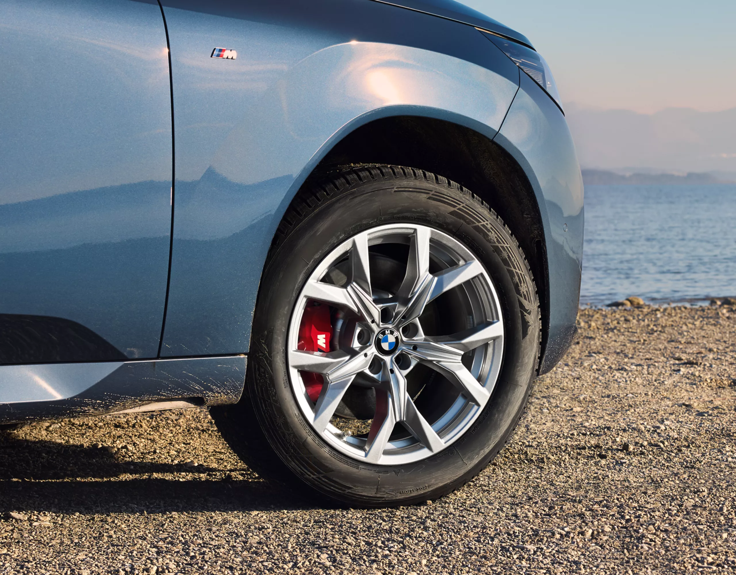 BMW steht auf verschneiter Straße – Detailansicht des Winter-Komplettrads 18'' BMW Leichtmetallrad Y-Speiche 921 Refined Silver, Winter-Komplettrad 