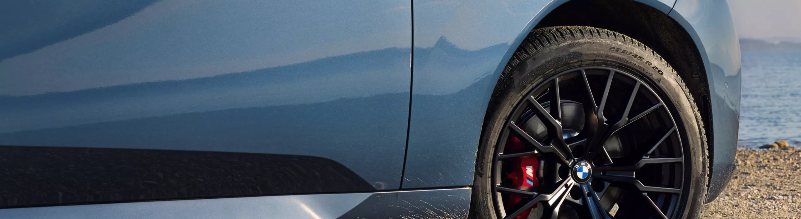 BMW stands on rocky beach – detailed view of wheel