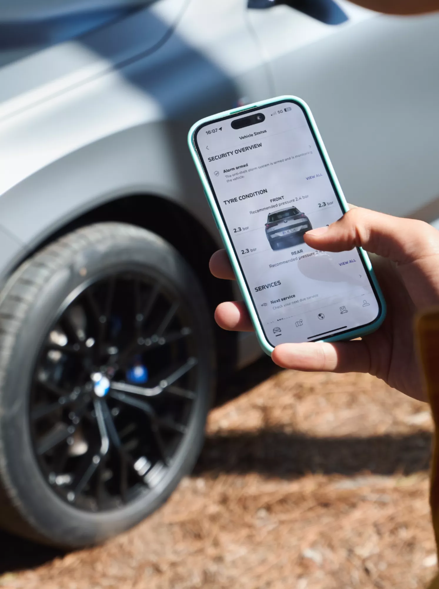Person standing in front of a BMW, using a smartphone