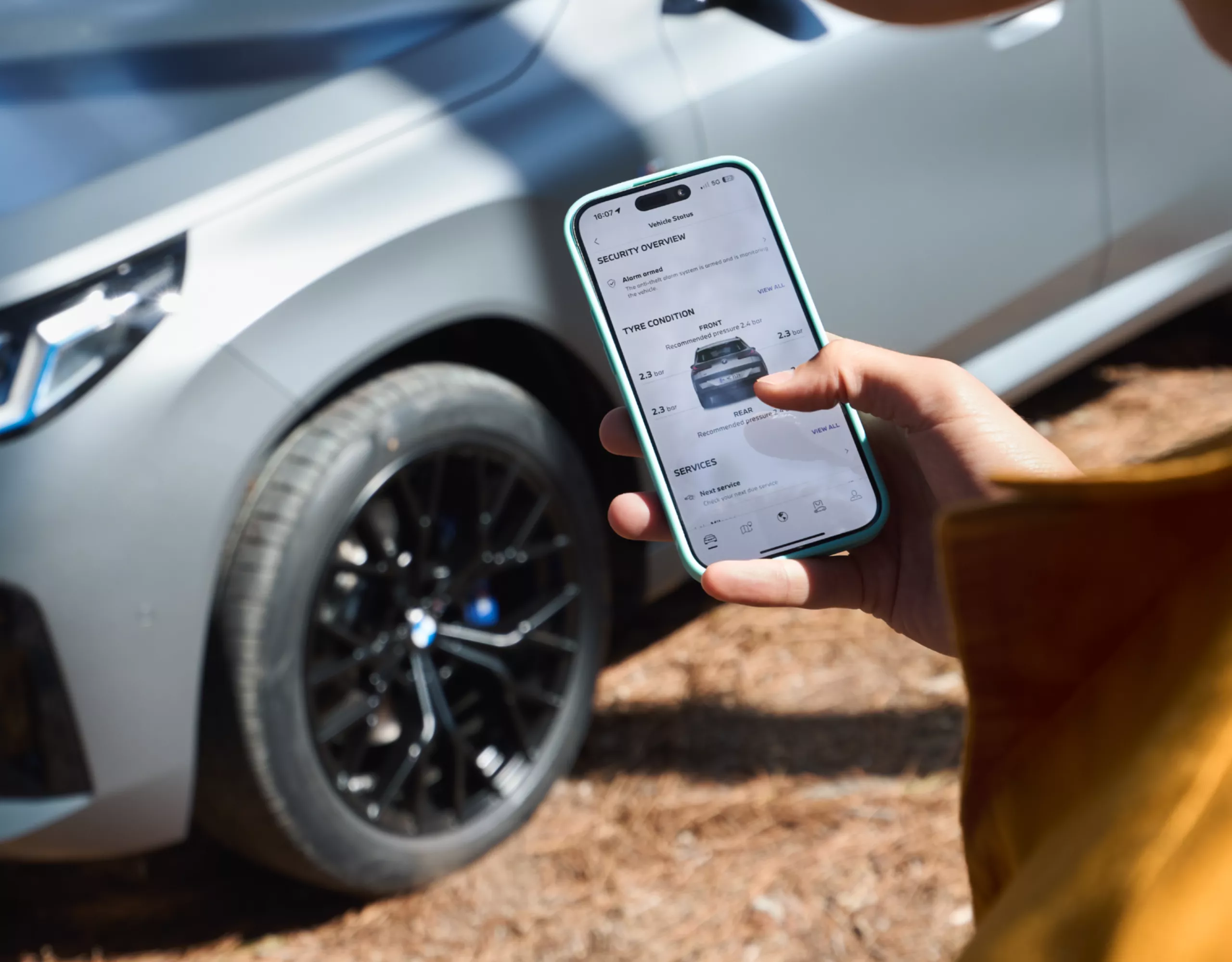 Person steht vor einem BMW und bedient ein Smartphone