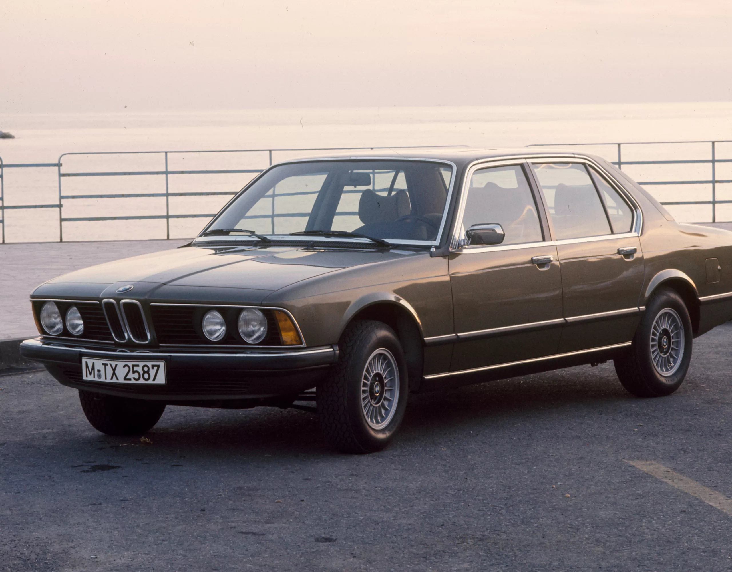 BMW 7er Limousine E23 geparkt am Meer mit einer Steinmole im Hintergrund