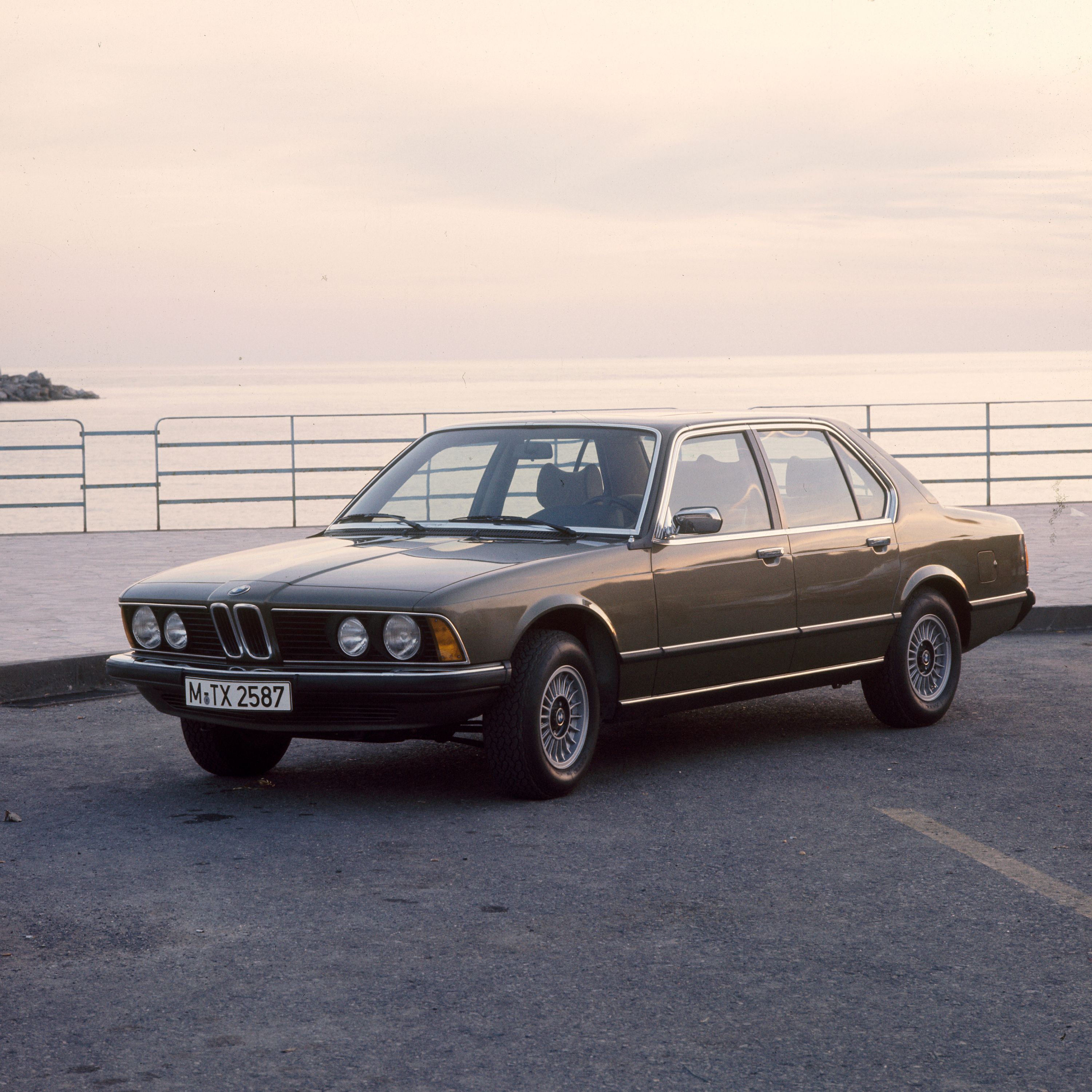 BMW serije 7 Limuzina, E23, parkiran pred morjem s kamnitim pomolom v ozadju