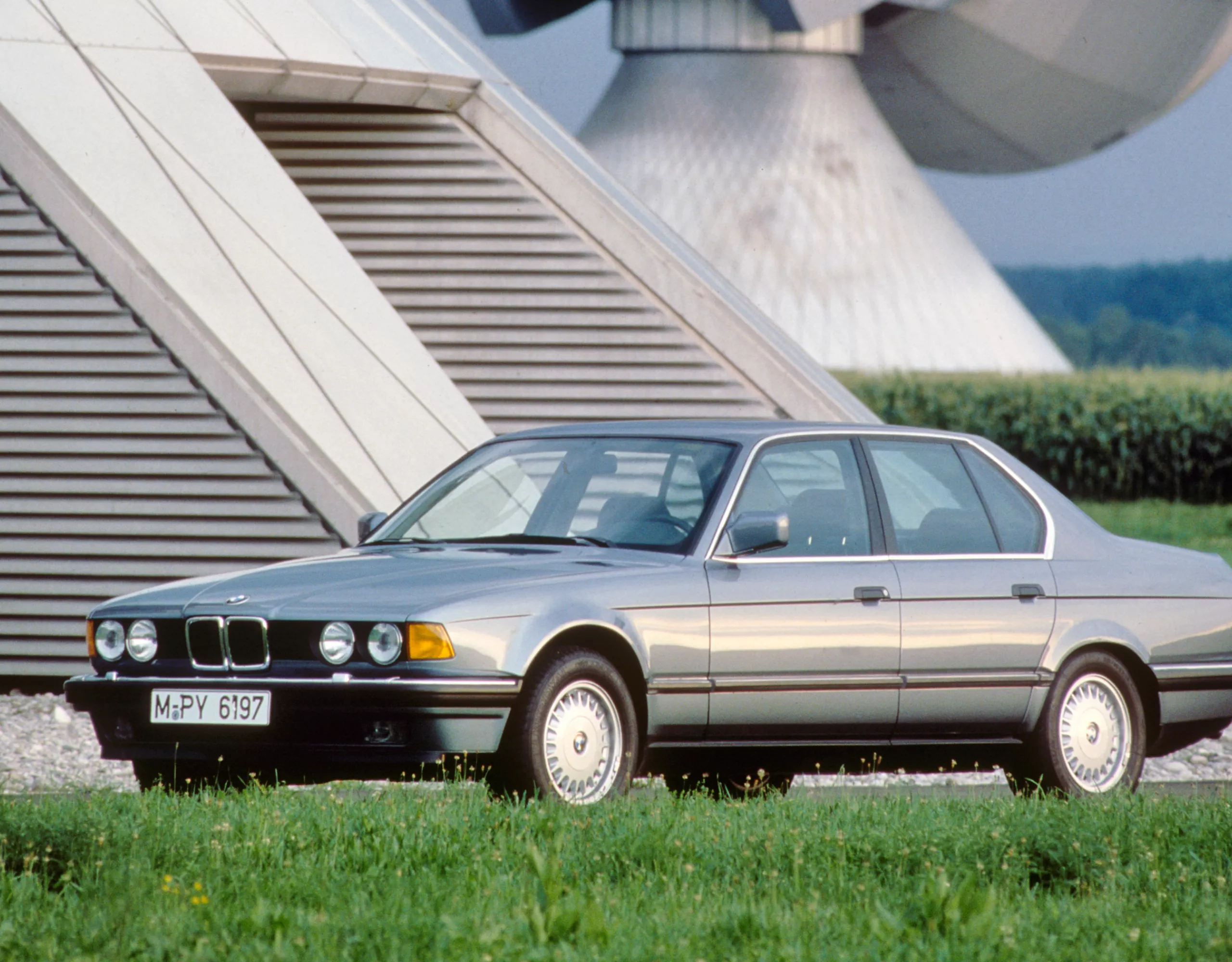 BMW 7er Limousine E32 in landwirtschaftlicher Umgebung umgeben von Feldern und Agraranlagen