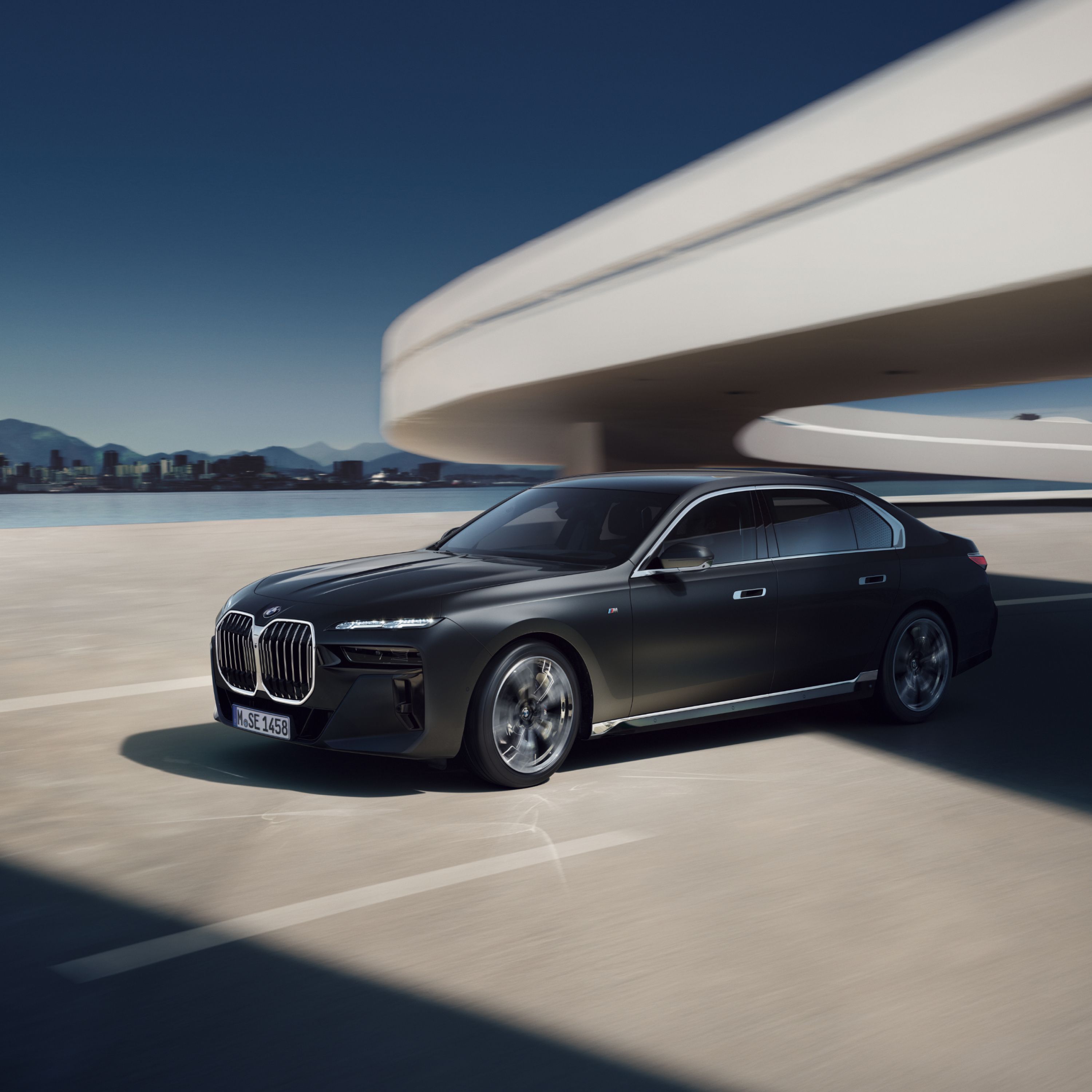 BMW Serie 7 Berlina G70 in movimento su un'autostrada futuristica con un panorama cittadino sullo sfondo