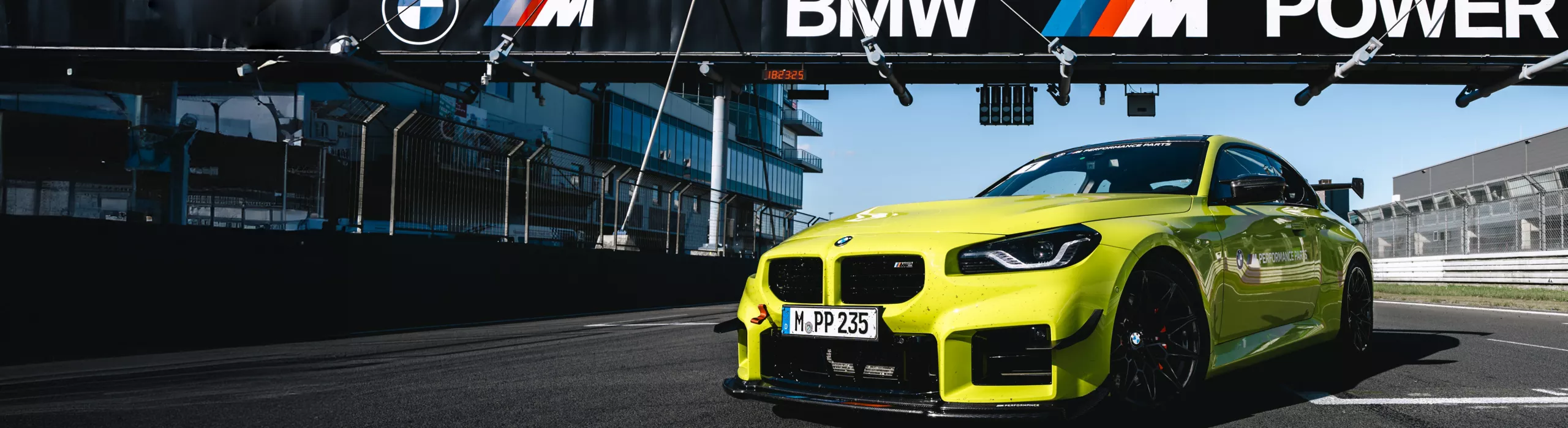 A BMW M2 a BMW M POWER híd alatt, egy versenypályán áll