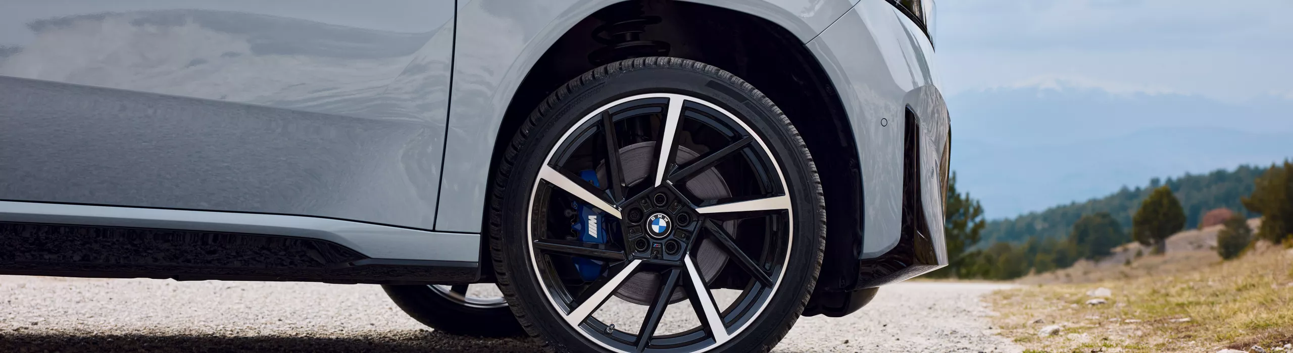 Könnyűfém keréktárcsa kék M Sport féknyereggel, BMW, első kerék kavicsos úton