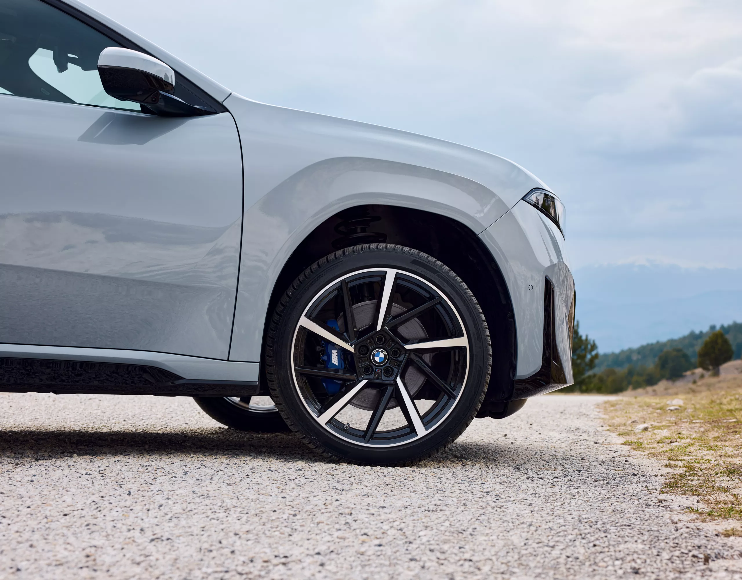 Könnyűfém keréktárcsa kék M Sport féknyereggel, BMW, első kerék kavicsos úton