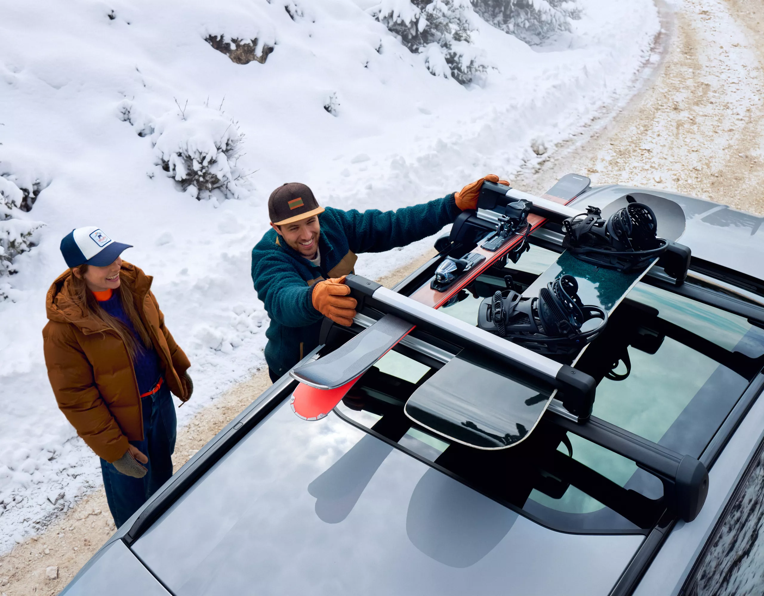 Porte-skis et porte-snowboards sur les barres de toit d'une BMW iX3, une personne fixe ses skis dans la neige