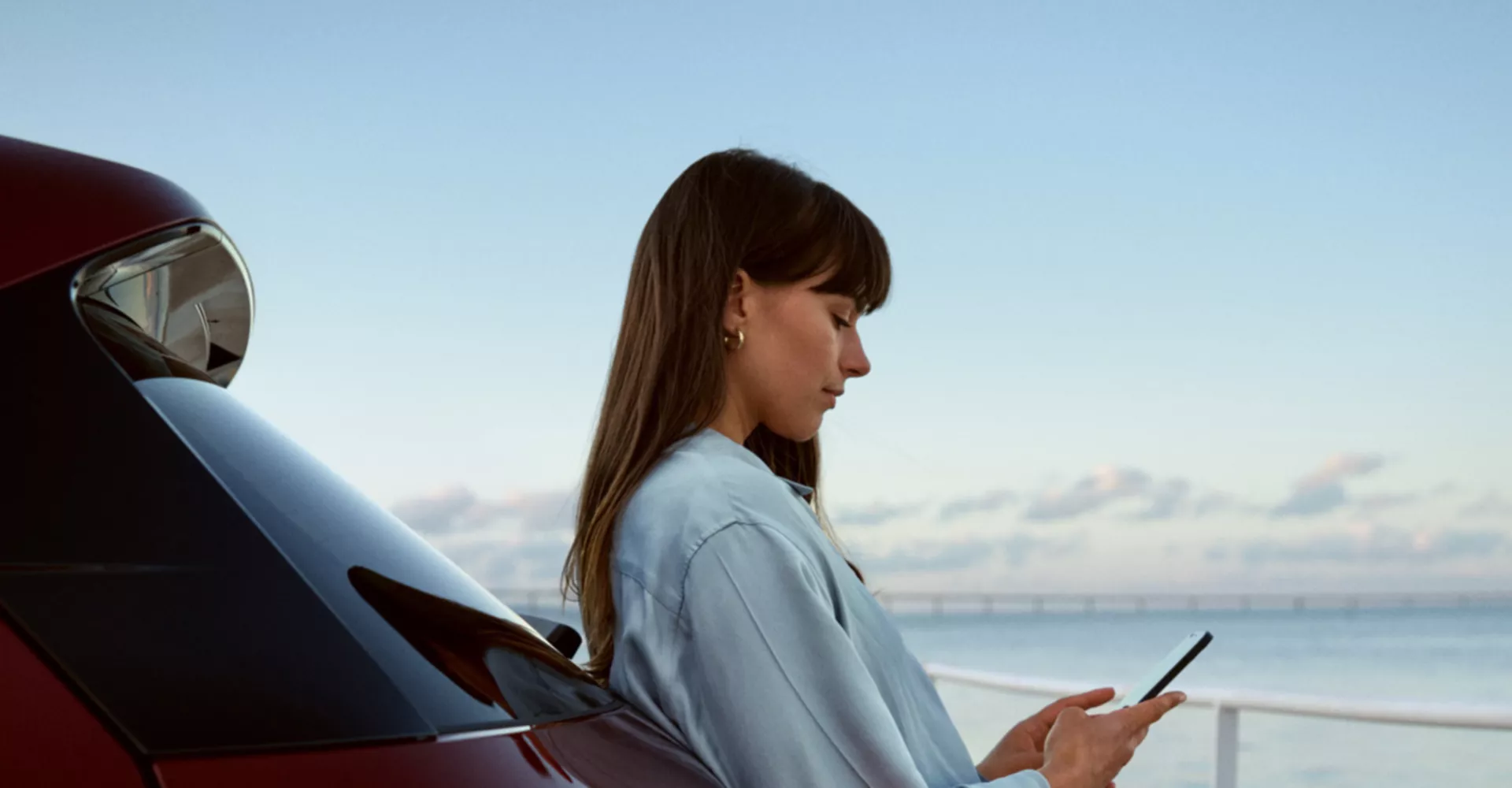 Woman checking mobile phone while leaning on BMW iX