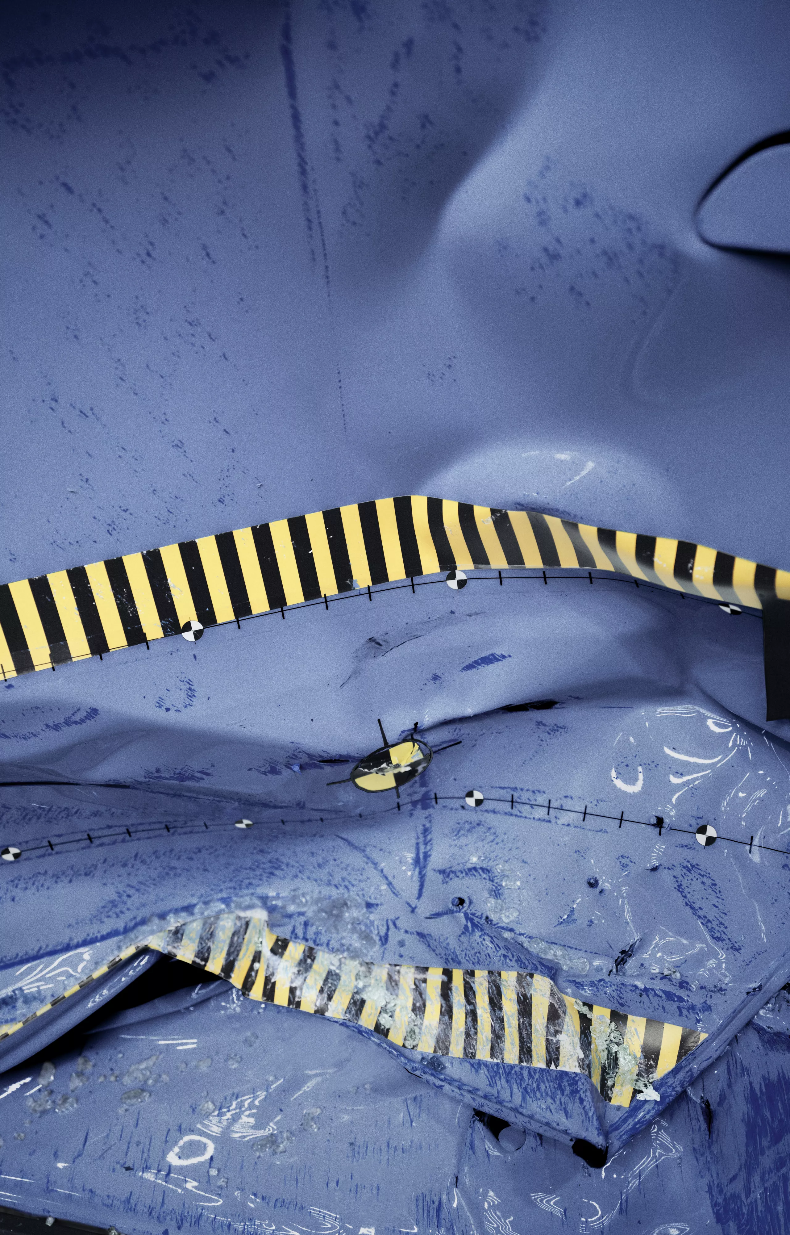 The image shows a digitally simulated, deformed car body with yellow and black markings following a crash test.