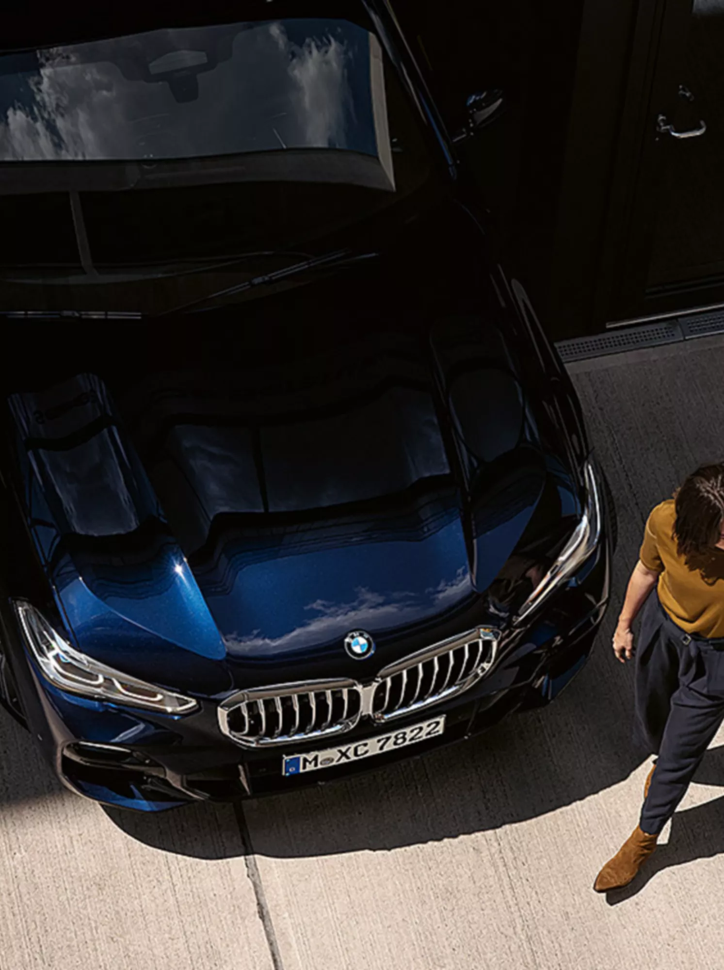 Woman and man walk past the front of the BMW.