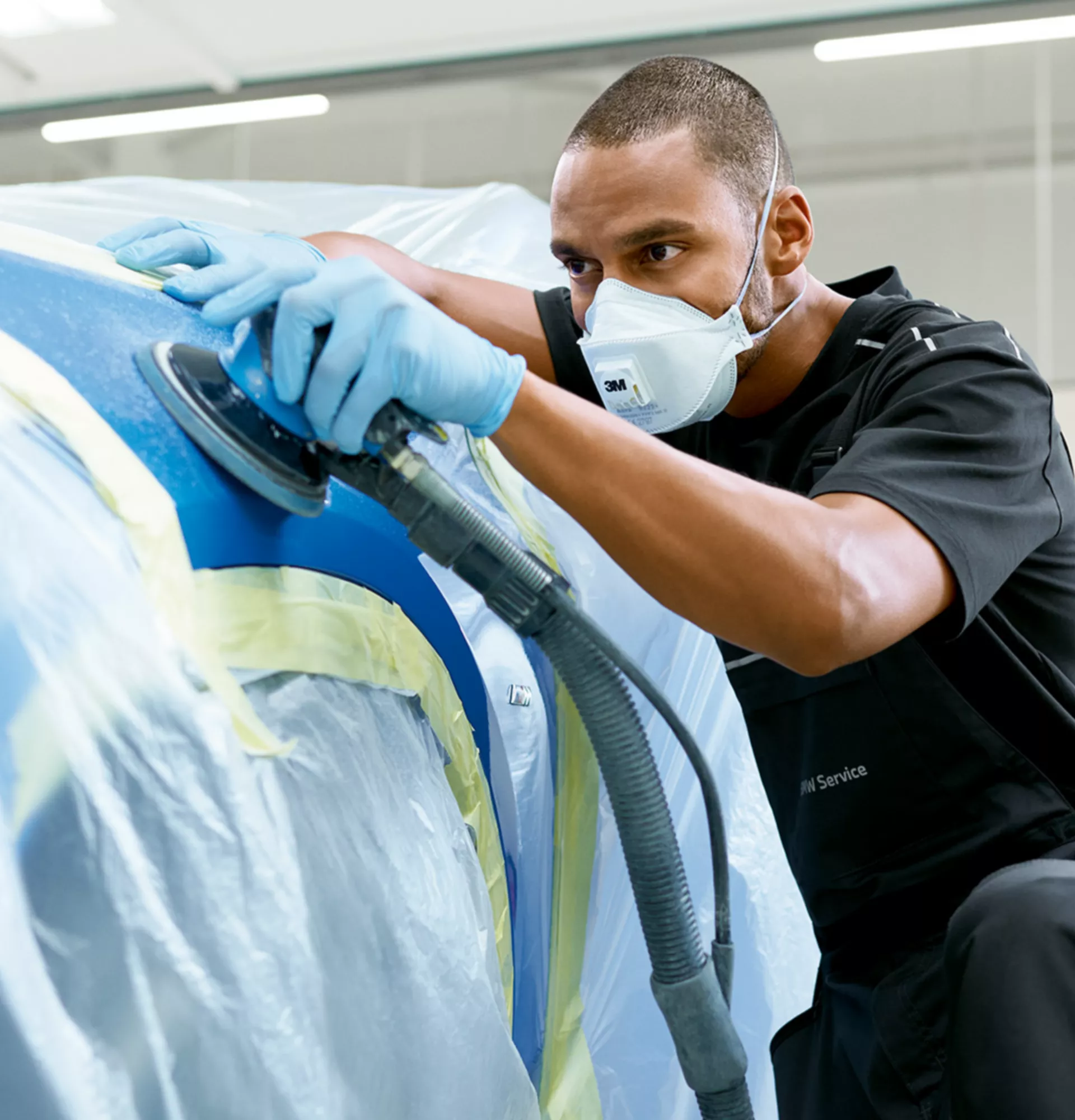 Man works on the foiled front wheel cover of a BMW with a polishing machine