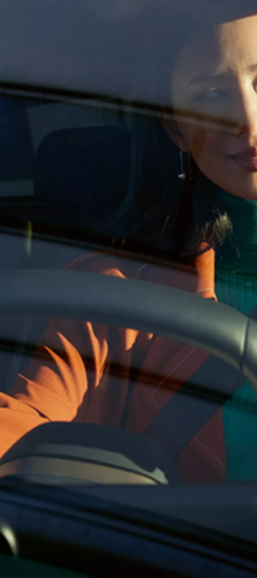 Una donna con una giacca arancione è seduta al posto di guida di una BMW
