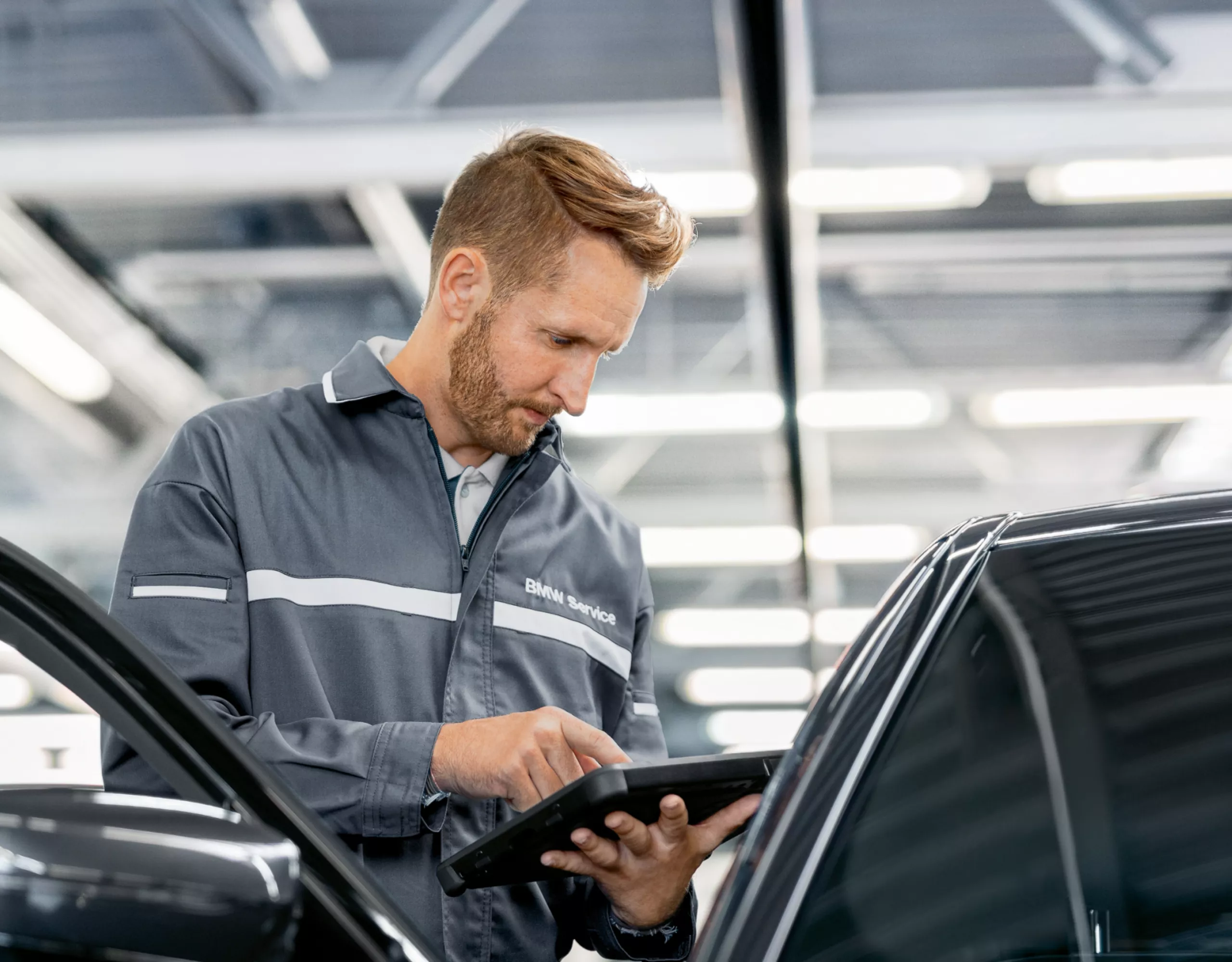 Un collaborateur d’un concessionnaire BMW utilise sa tablette devant une BMW.