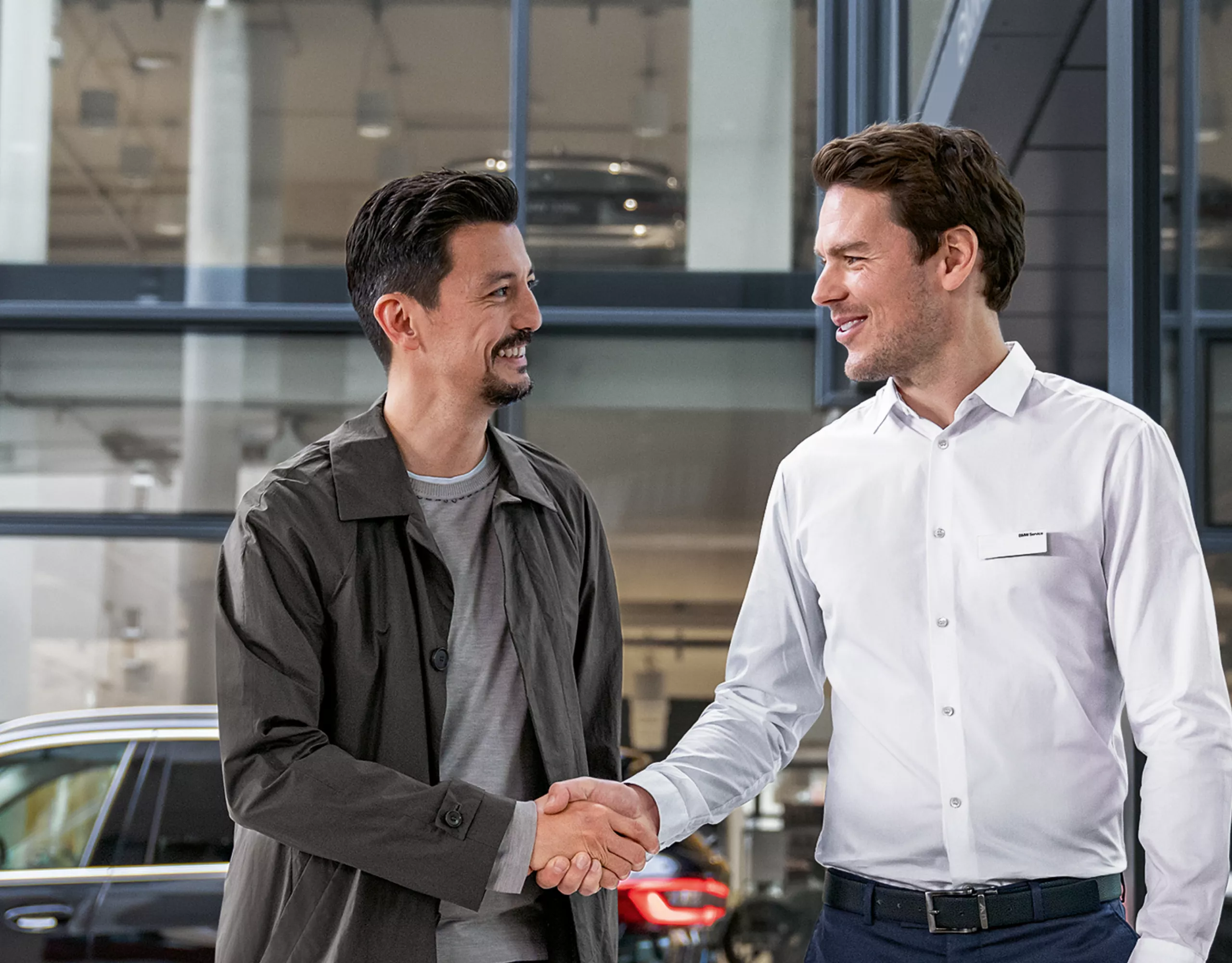 Deux hommes se serrent la main chez un concessionnaire BMW.