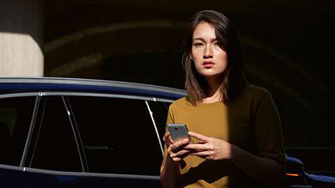 BMW ConnectedDrive overview woman with smartphone in front of BMW