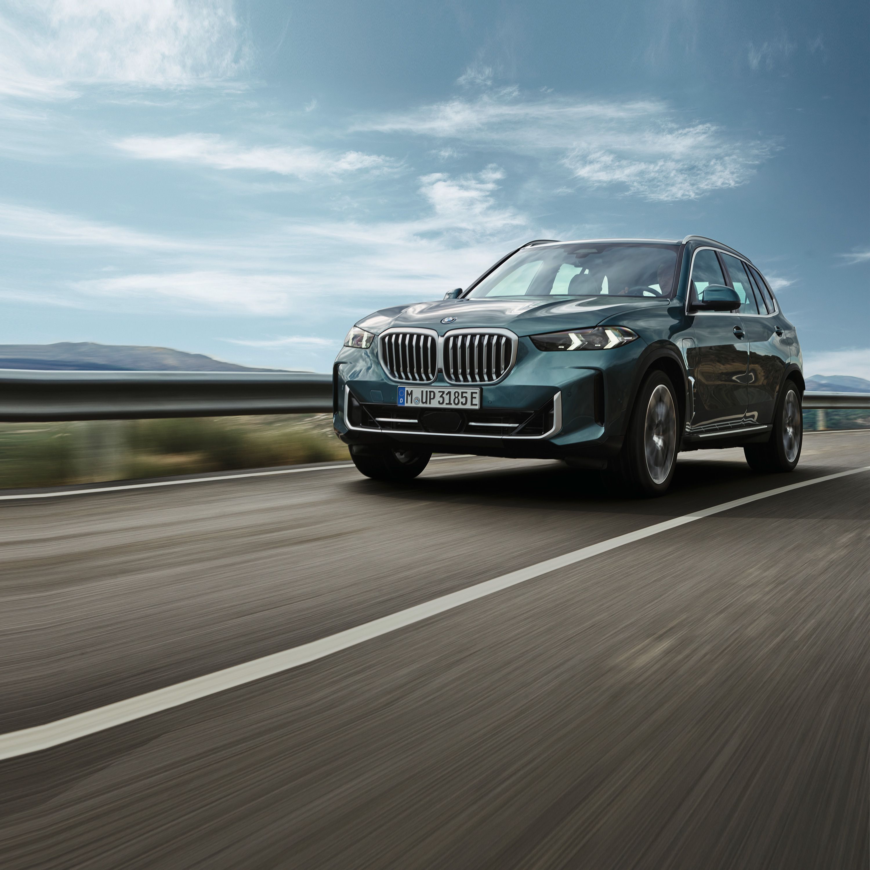 SUV BMW X5 na tle zachodzącego słońca.