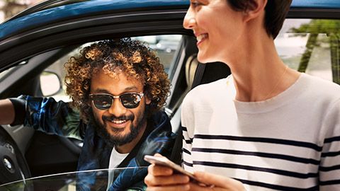 BMW Financial Services, άντρας κάθεται μέσα σε μία BMW και γυναίκα με smartphone