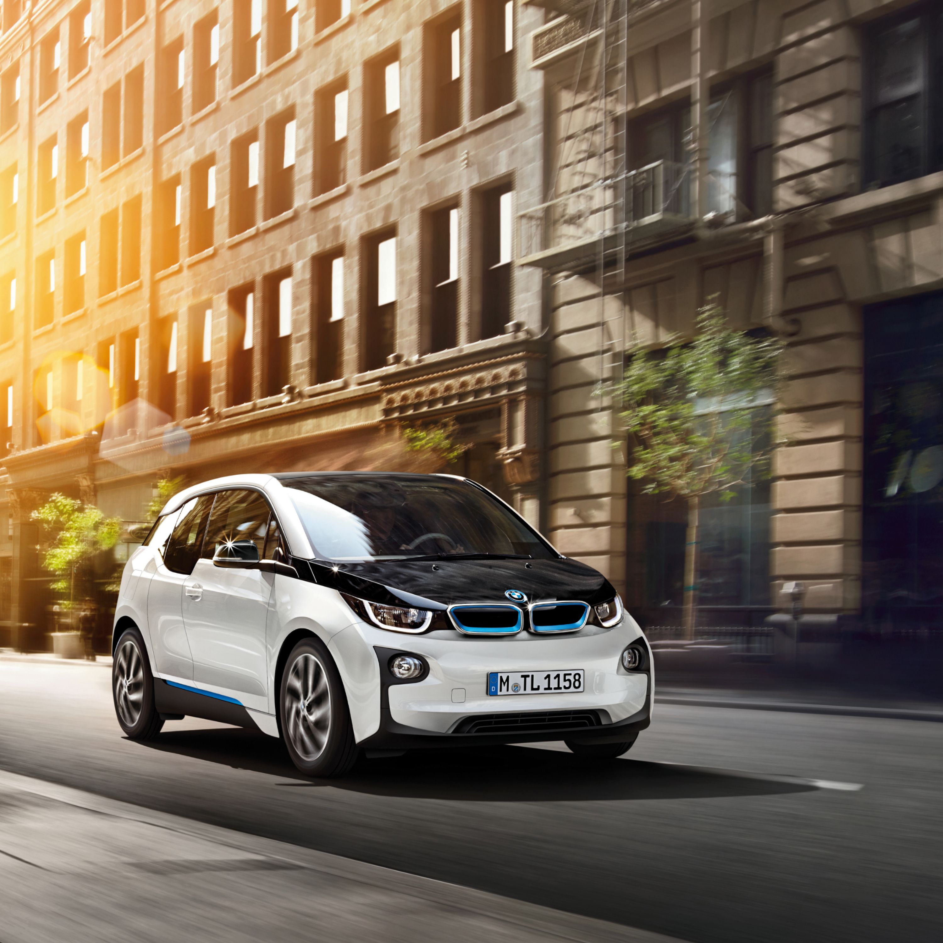 White BMW i3 electric small car driving in front of Roman architecture