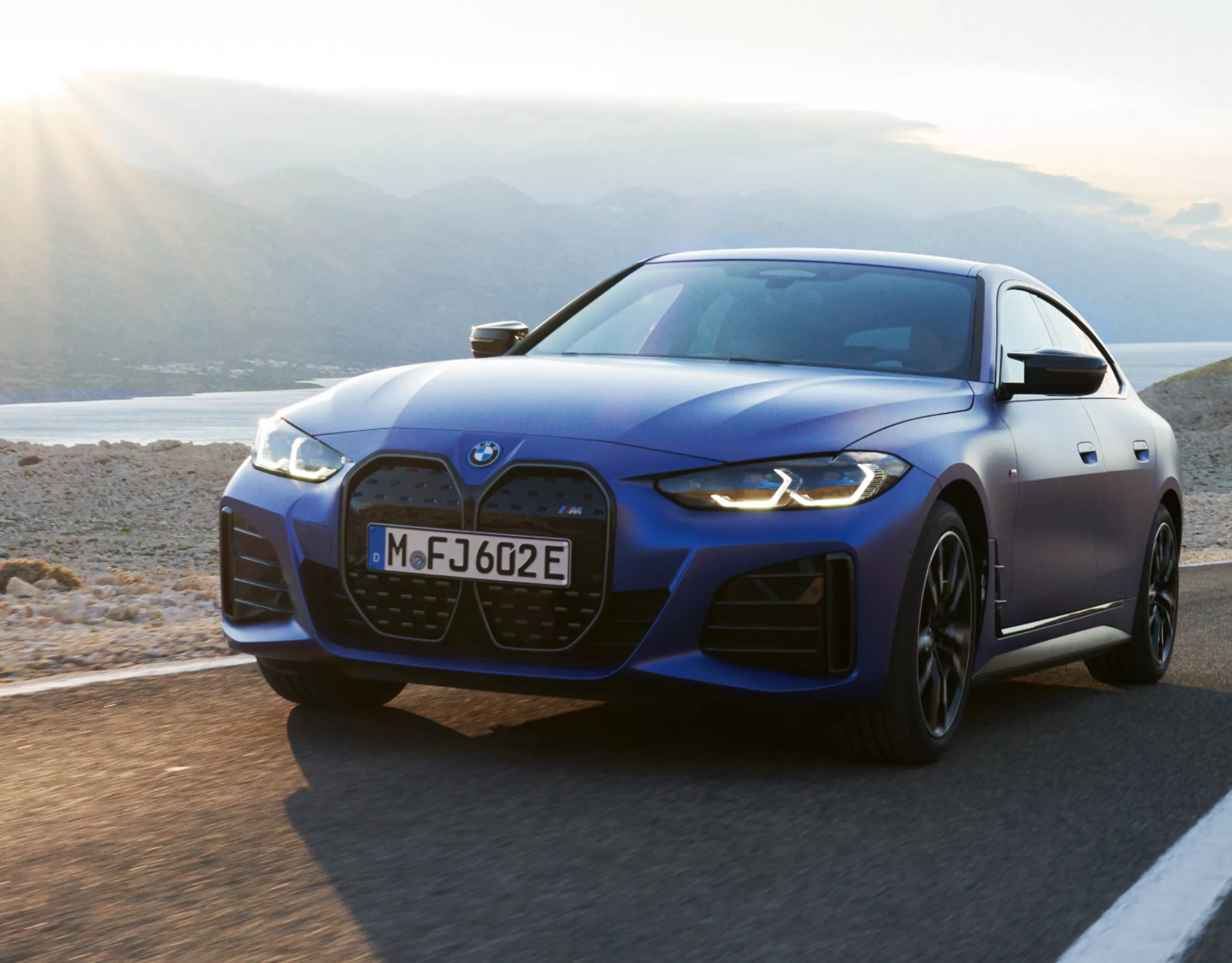 BMW i4 M50 Gran Coupé Mineralweiss Metallic roulant à grande vitesse sur une large route désertique