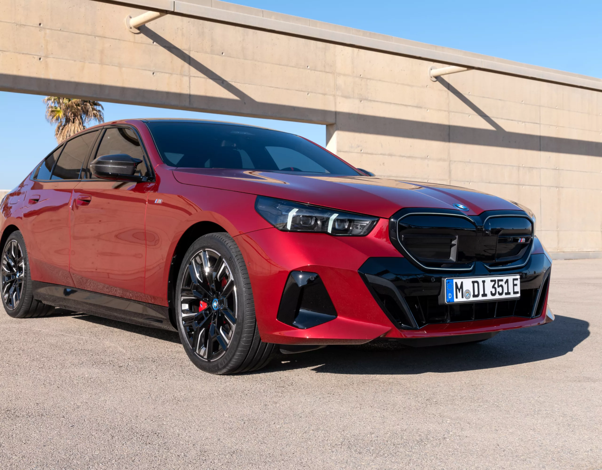 BMW i5 Berline M60 xDrive en Fire Red Metallic, garée au dernier étage d'un parking lumineux