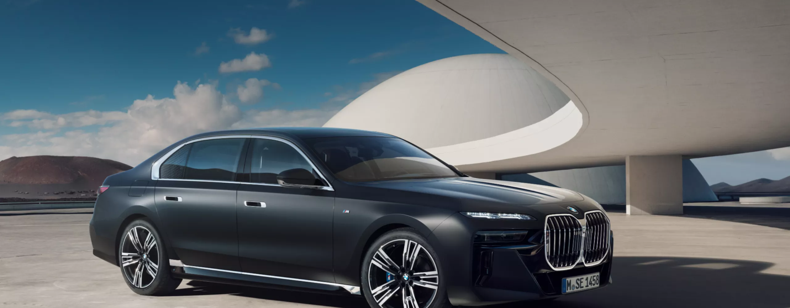 Luksusowe BMW serii 7, widok z zewnątrz na tle nowoczesnego budynku.