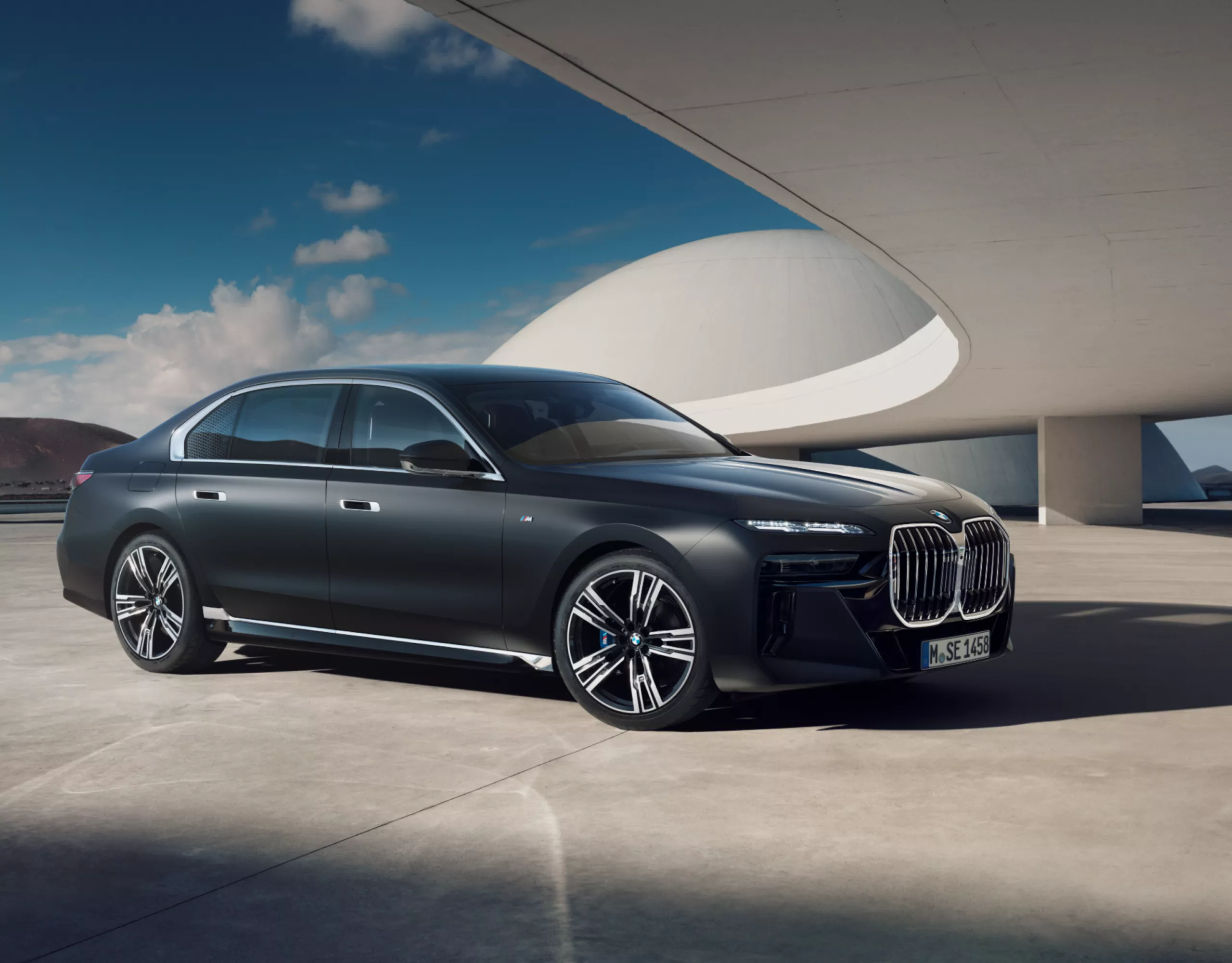 BMW i7 Berline en Frozen Deep Grey metallic, garée sous le toit d'un immeuble futuriste