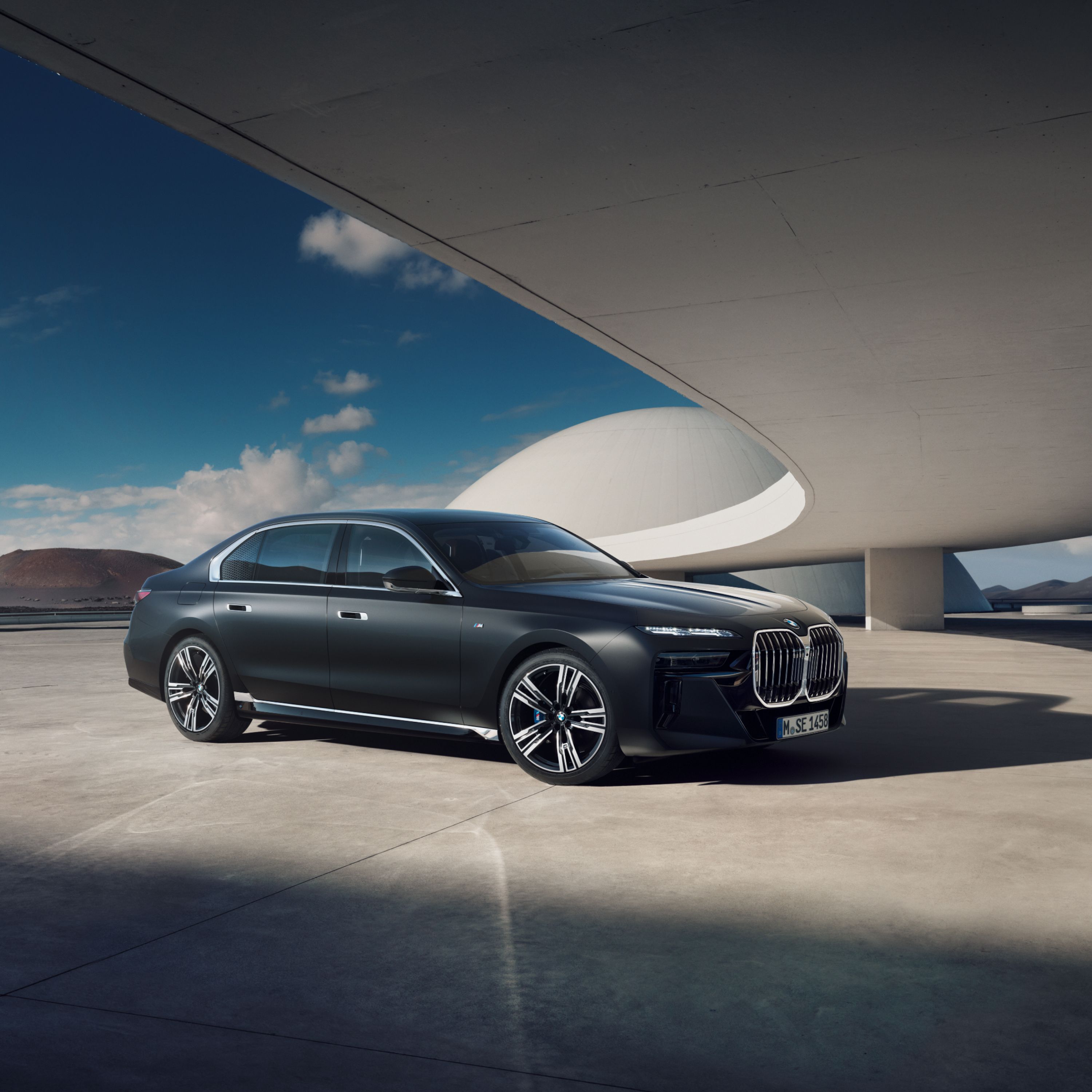 BMW i7 Limousine in Frozen Deep Grey metallic, geparkt unter dem Dach eines futuristischen Gebäudes