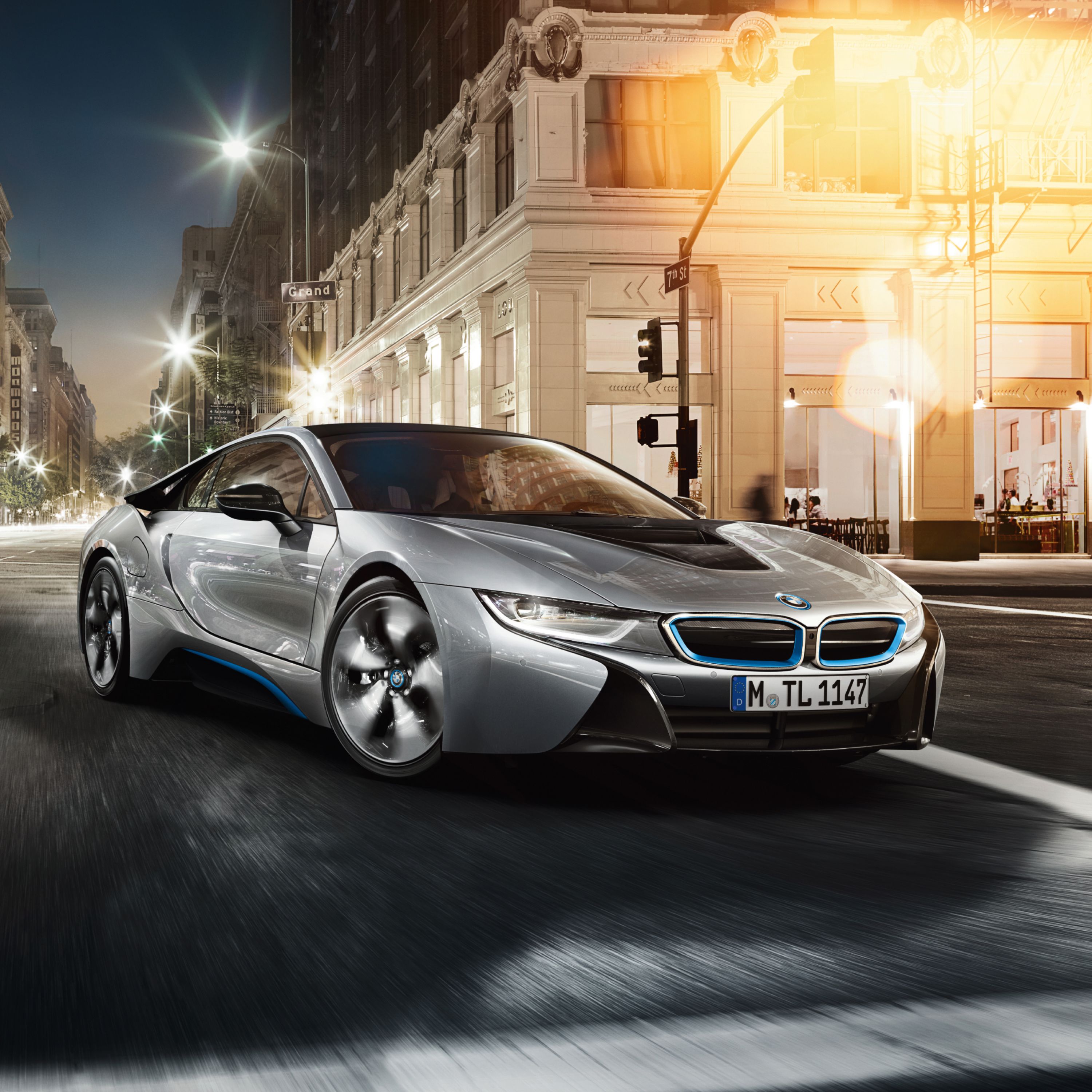 Srebrny sportowy samochód hybrydowy plug-in BMW i8 zaparkowany przed Grand Hotelem w dużym mieście