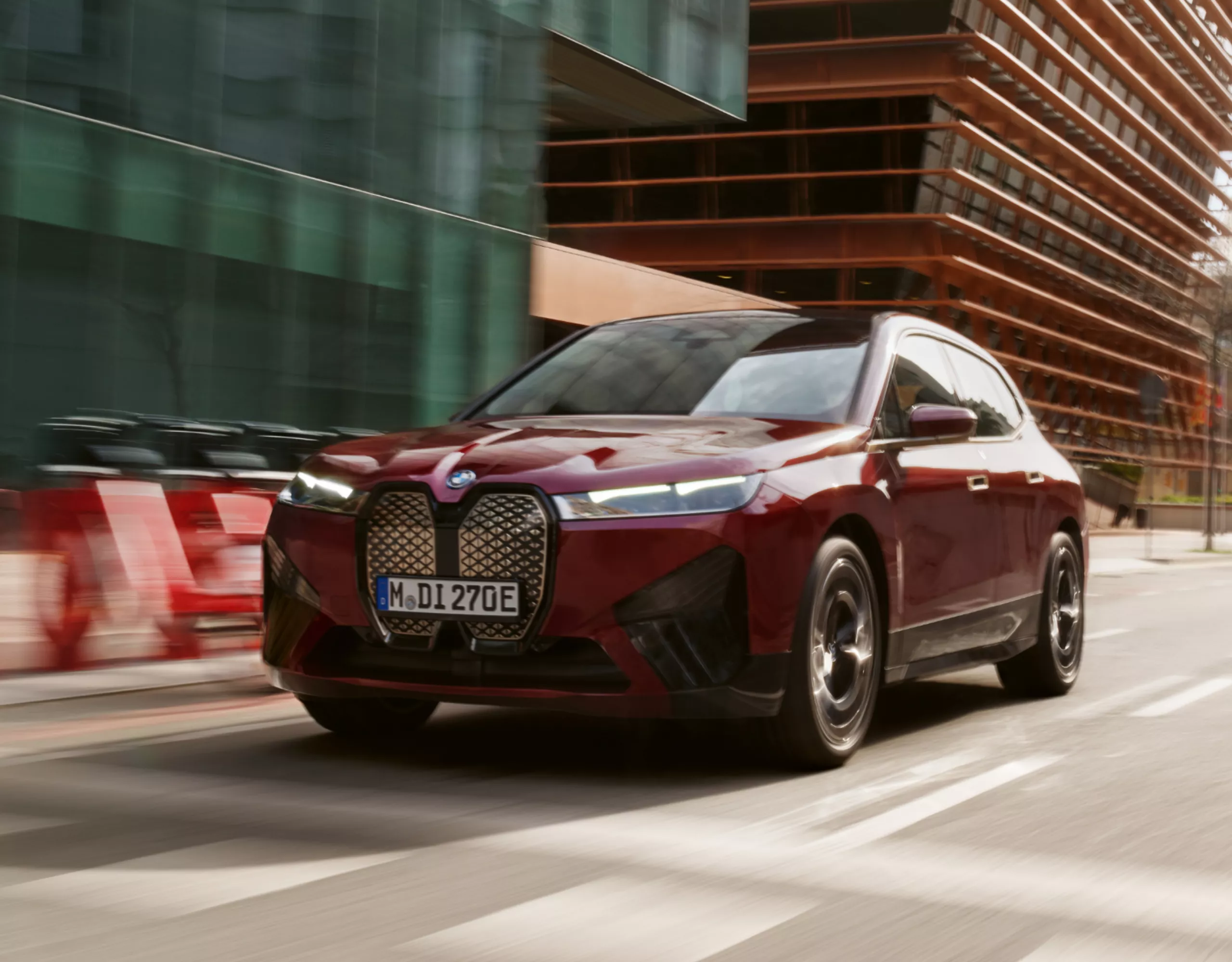BMW iX Electric SUV en Aventurinrot sur une route principale dans un cadre urbain