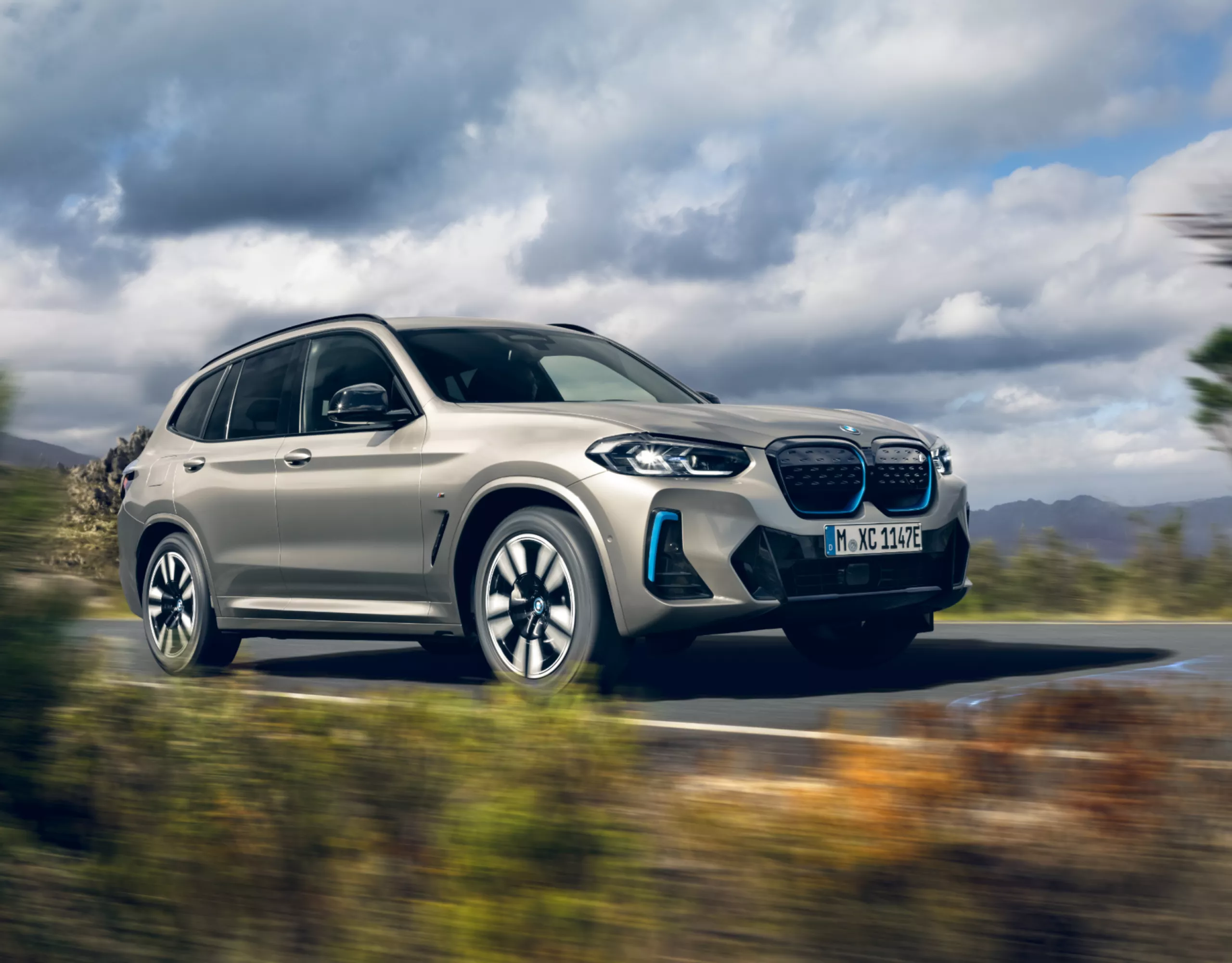 BMW iX3 SUV électrique en Kaschmirsilber metallic en mouvement sur une route méditerranéenne