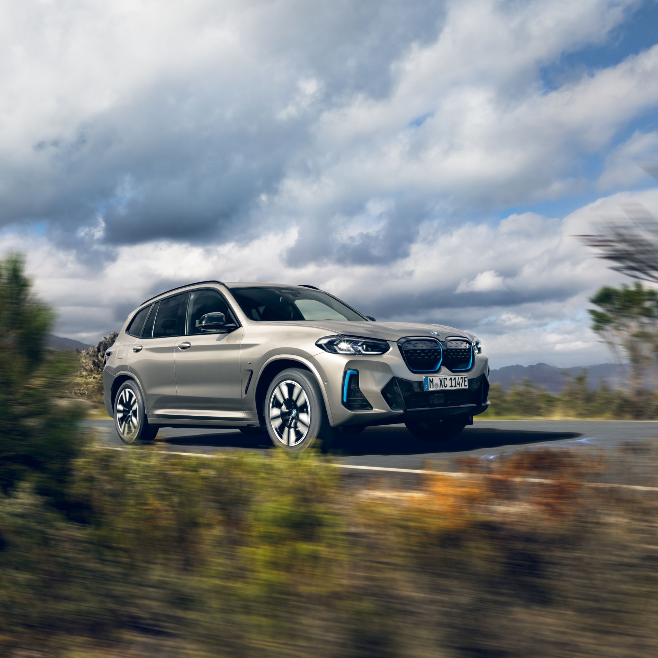 BMW iX3 SUV électrique en Kaschmirsilber metallic en mouvement sur une route méditerranéenne