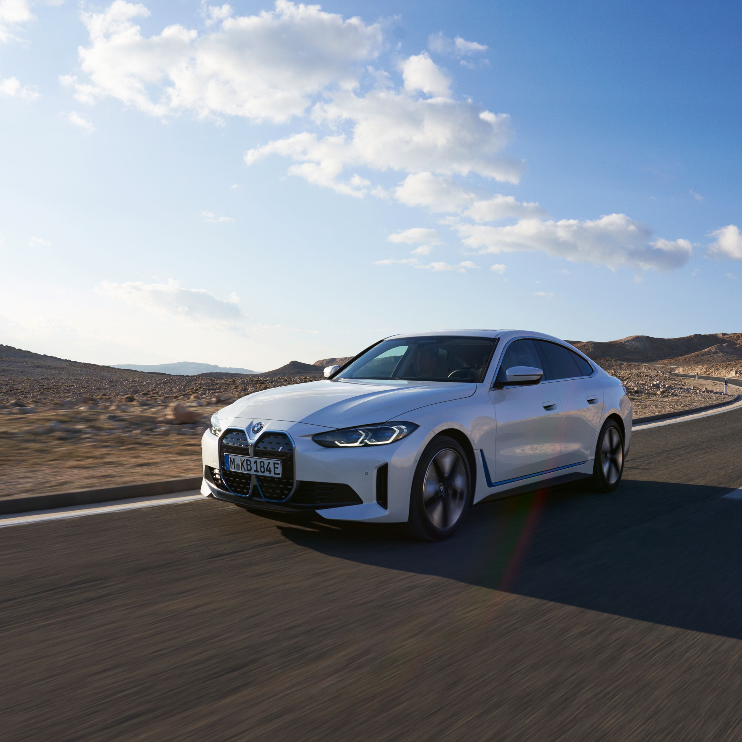 BMW i4 Gran Coupé en Mineralweiss Metallic roulant à grande vitesse sur une large route désertique