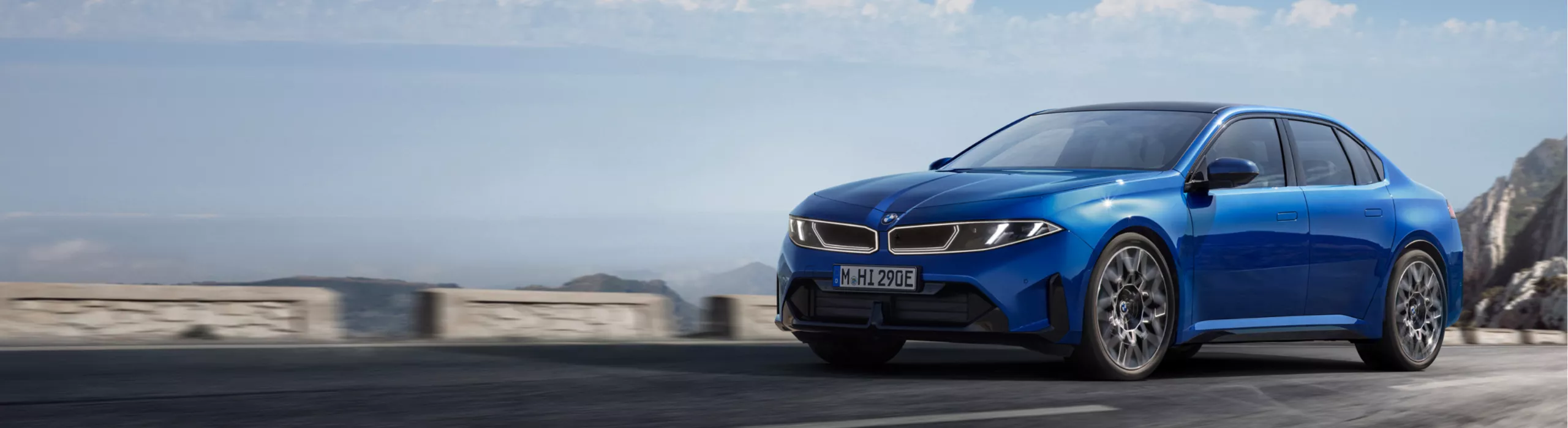 El BMW i3 Berlina apareciendo ante una pared gris claro y deteniéndose mostrando su perfil lateral.