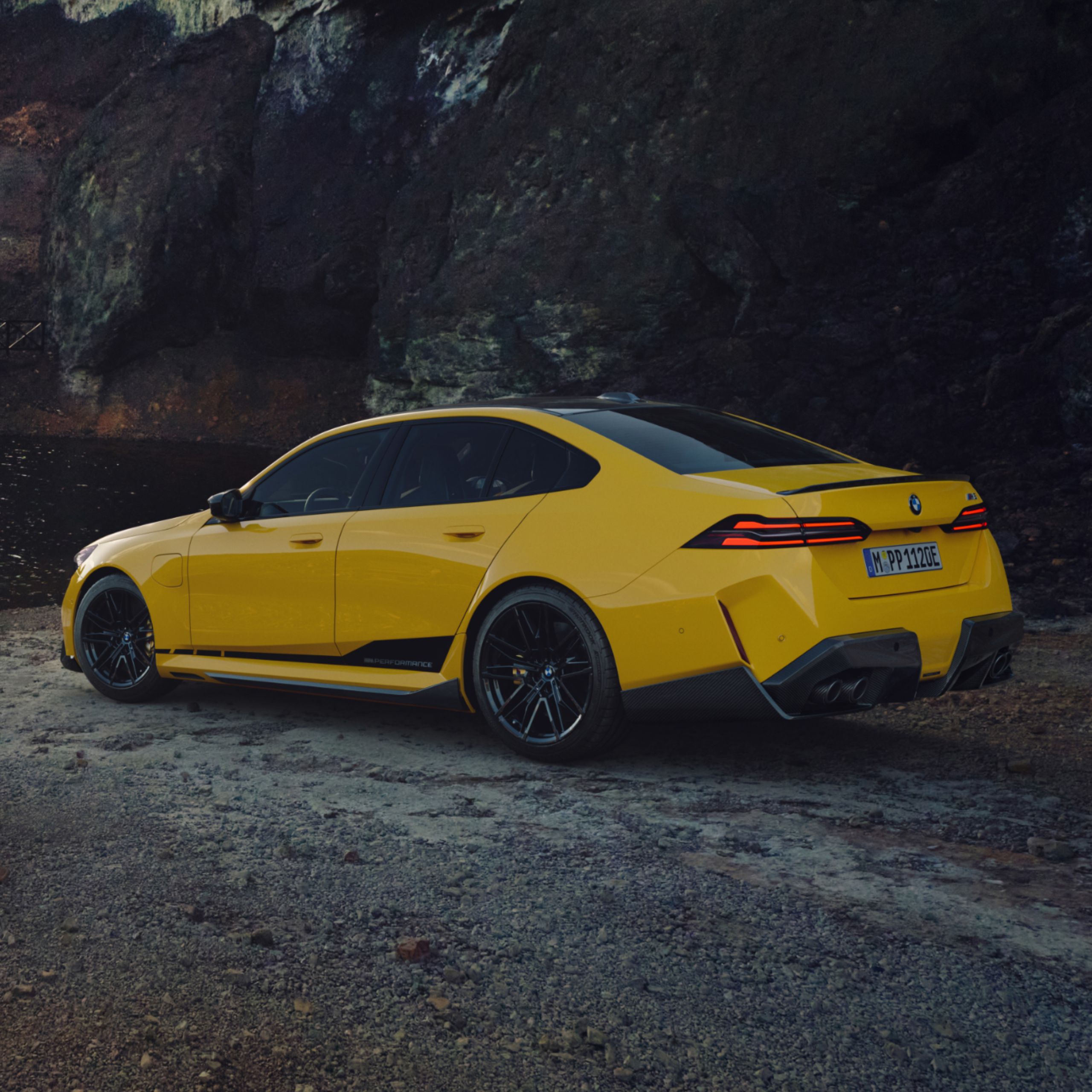 BMW M4 met BMW M Performance wrapping Motorsport staat bij een rivier met bergen op de achtergrond