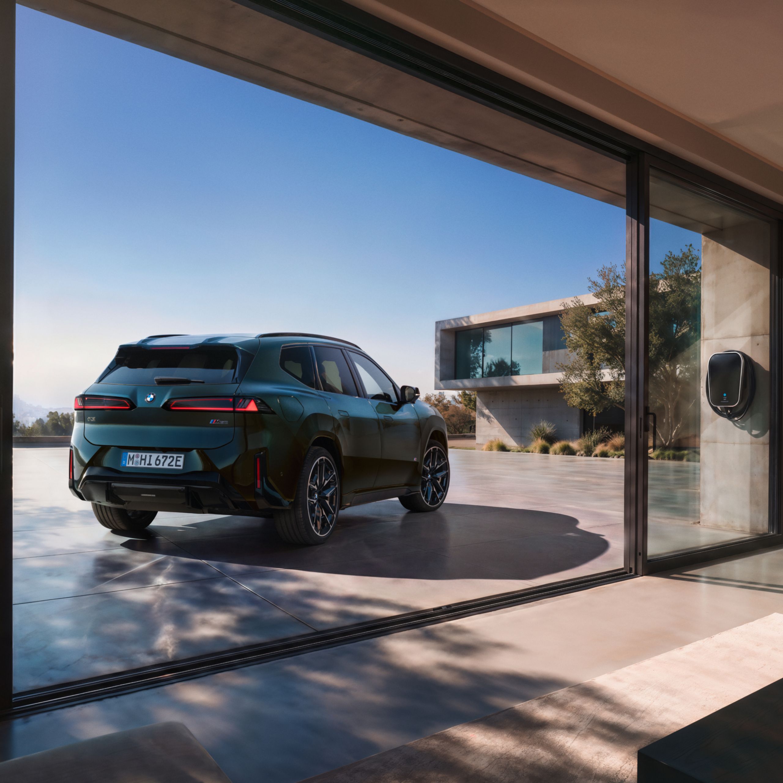 The BMW iX3 M60 xDrive parked in front of a modern parking garage