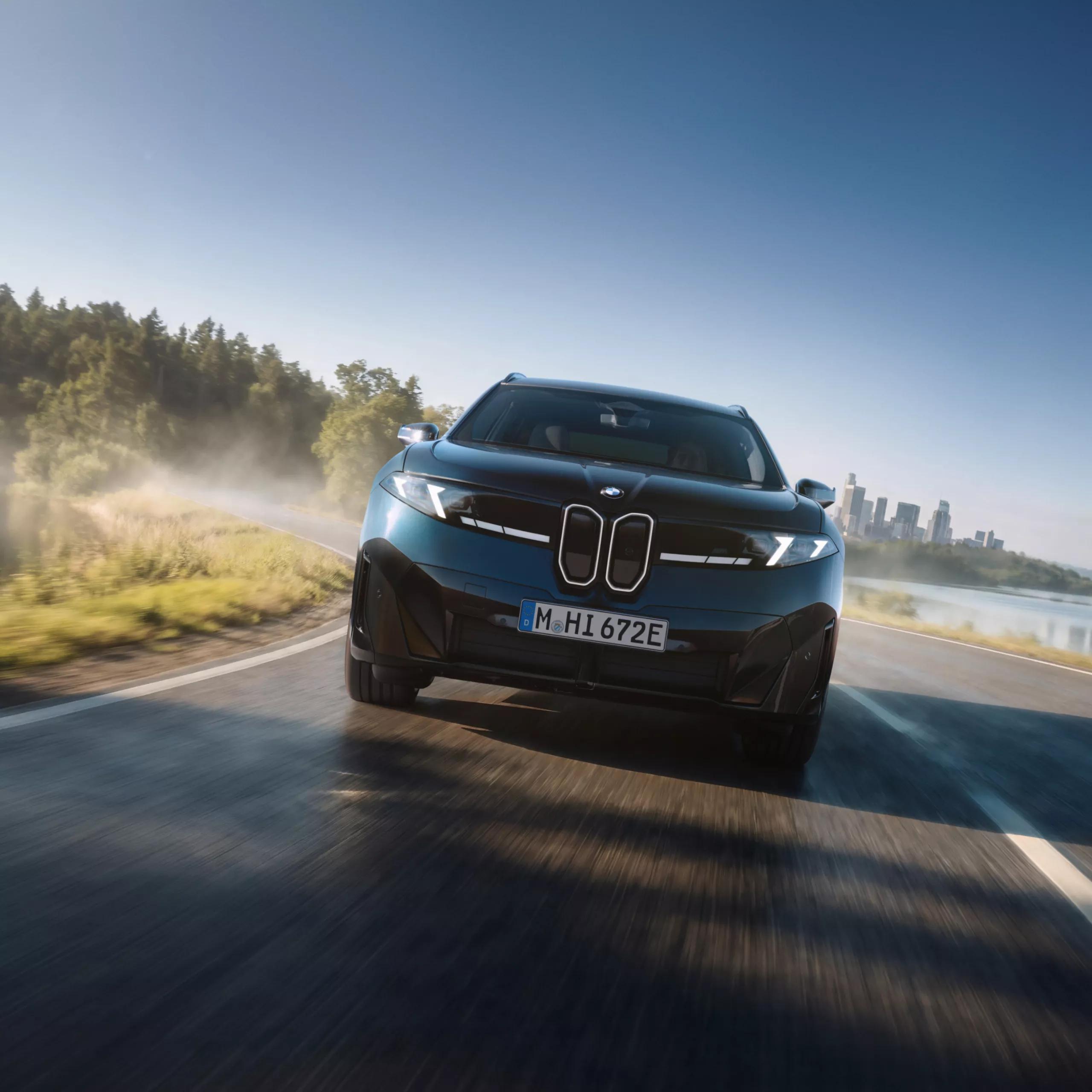 BMW iX3 M60 xDrive driving on a winding road from front perspective