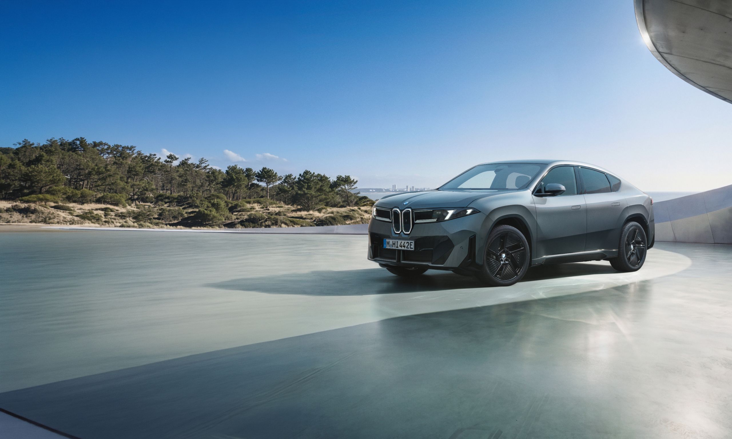 The BMW iX4 parked on a modern shimmering surface