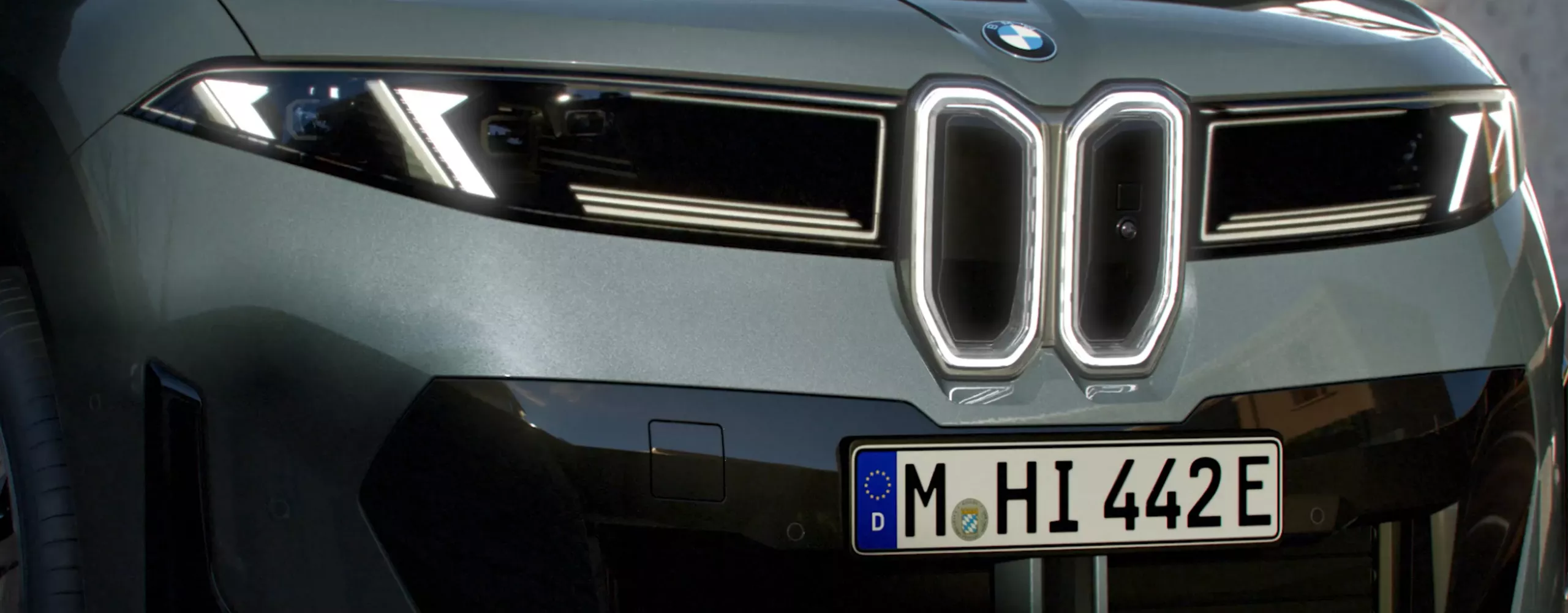 Front view of the BMW iX4 50 xDrive with illuminated Iconic Glow kidney grille and headlights.