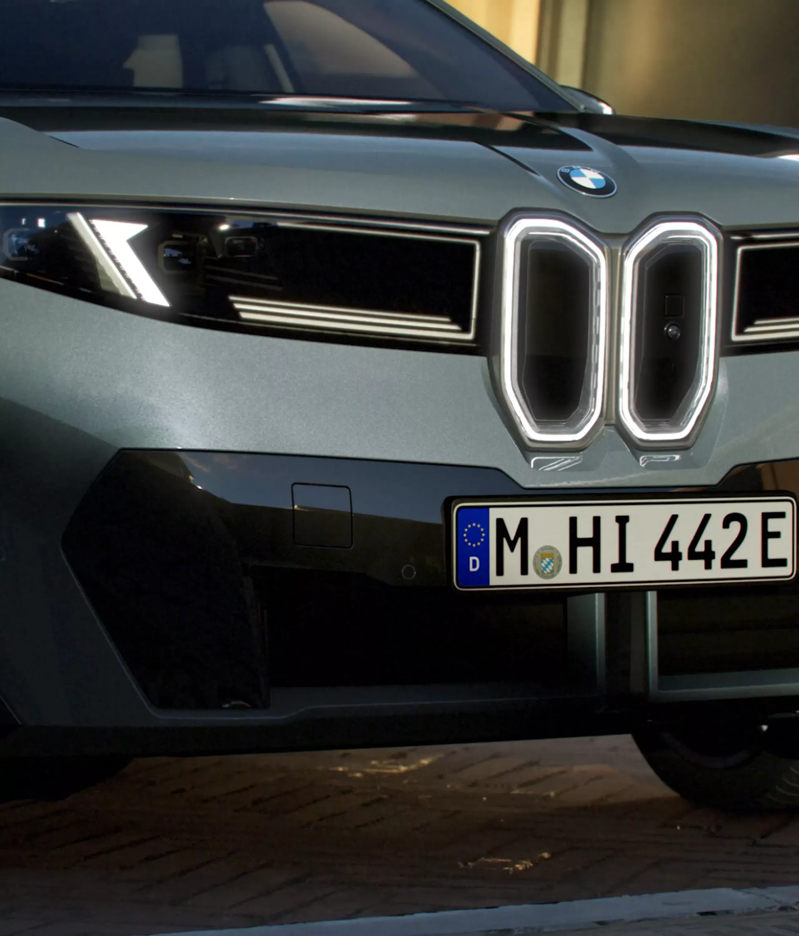 キドニー・グリルを輝かせるBMWアイコニック・グローとヘッドライトを備えた、BMW iX4 50 xDriveのフロント・ビューです。