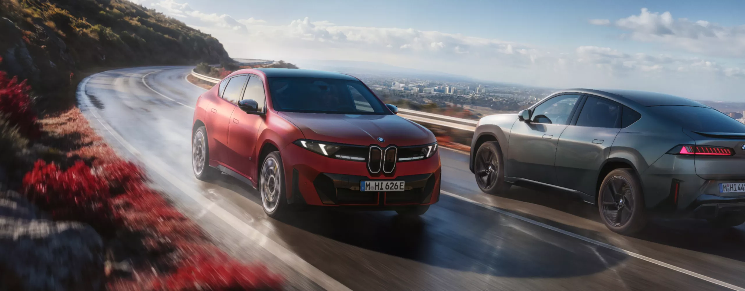 Twee nieuwe BMW iX4's komen elkaar tegen op een bergweg.