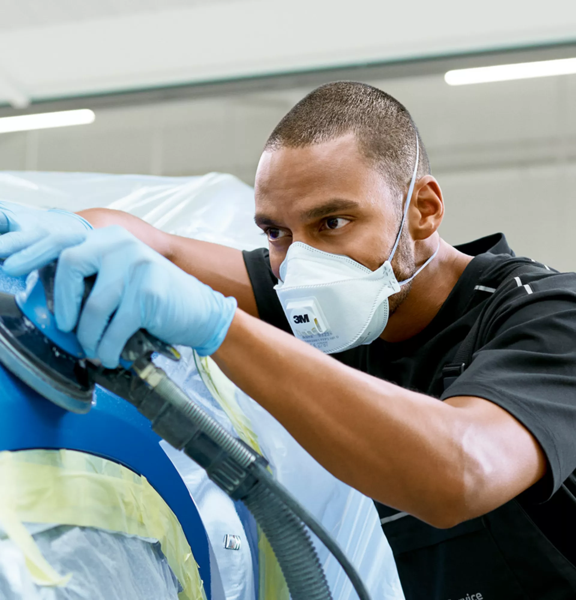 Man works on the foiled front wheel cover of a BMW with a polishing machine