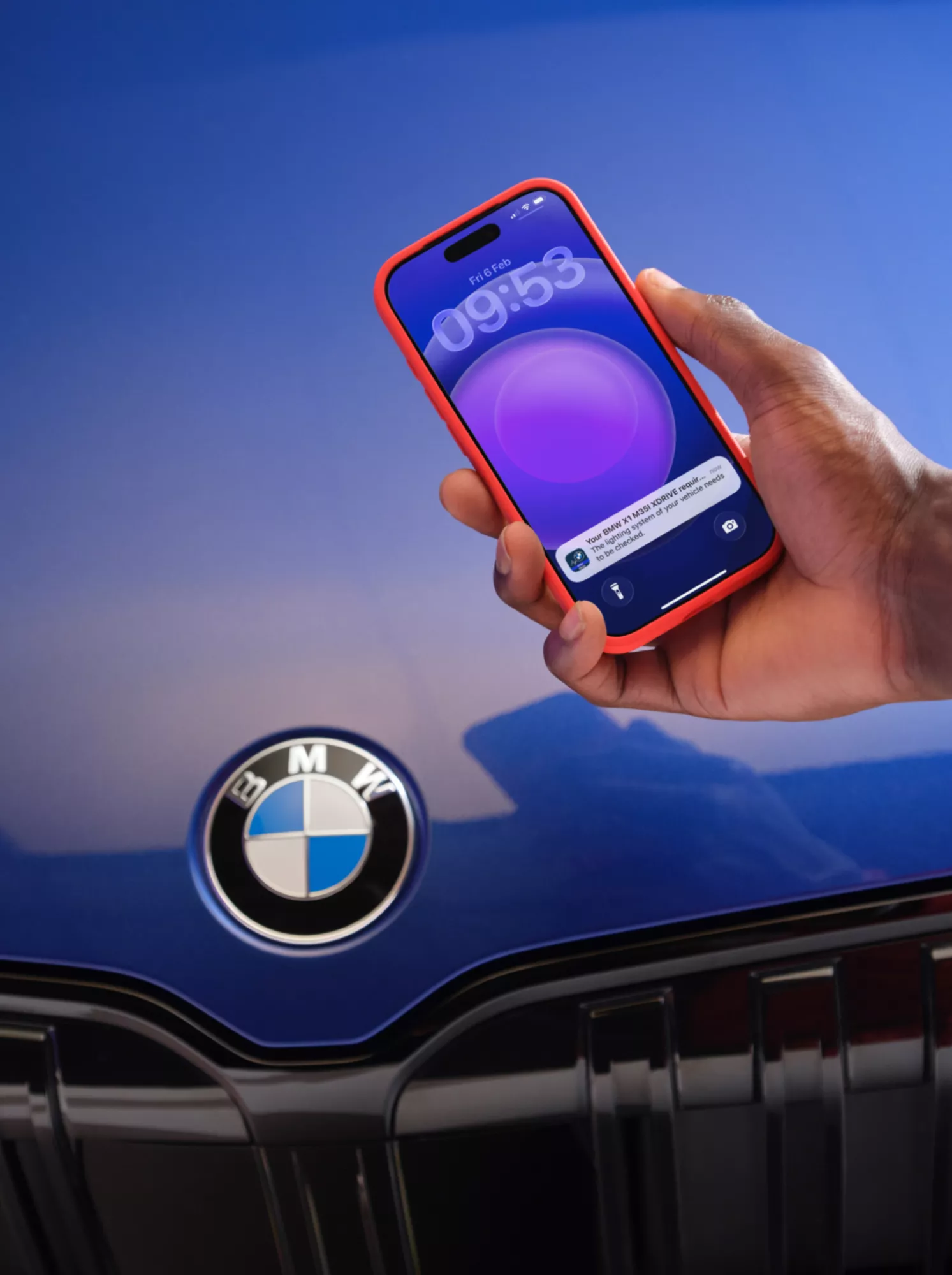 Uno smartphone è tenuto davanti a un cofano di colore lilla