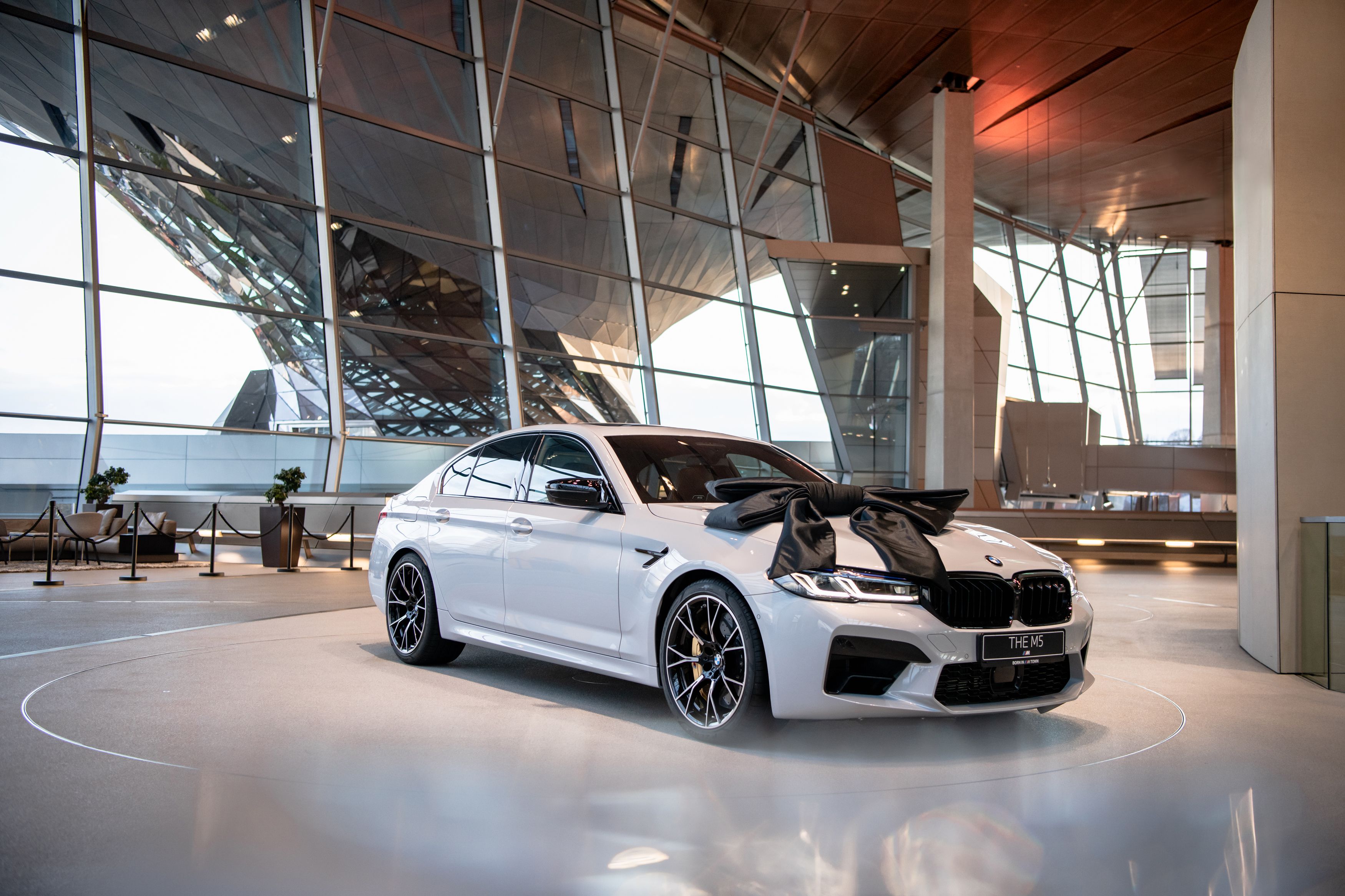 Weißer BMW M5 mit schwarzer Schleife auf der Abholungsplattform der BMW Welt